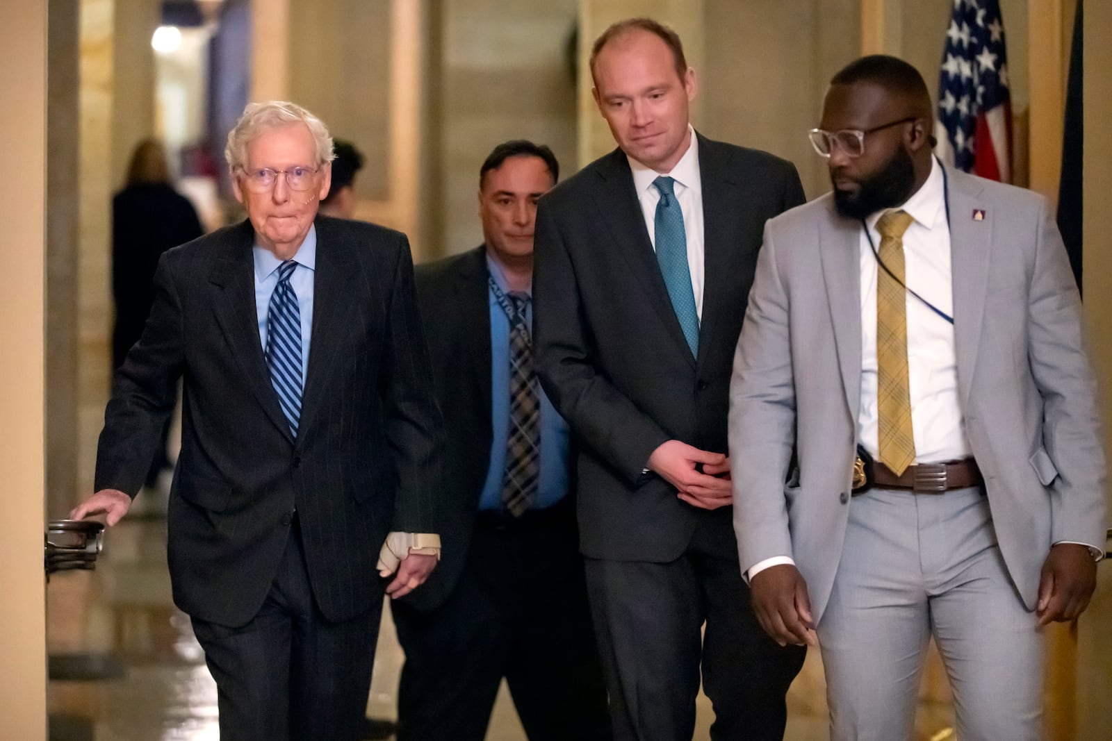 Senate Minority Leader Mitch McConnell of Ky., left, wears a bandage on his face and wrist as he walks to cast a vote on the Senate floor after falling during a luncheon on Capitol Hill, Tuesday, Dec. 10, 2024, in Washington. (AP Photo/Mark Schiefelbein)