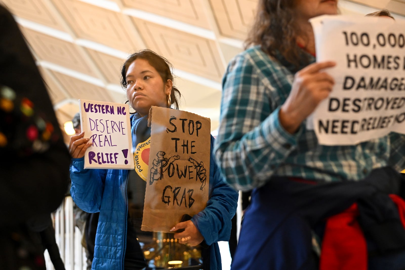 A protestor holds a sign as the Republican-dominated North Carolina House convened to complete the override of Gov. Cooper's veto, Wednesday, Dec. 11, 2024, in Raleigh, N.C. (AP Photo/Matt Kelley)