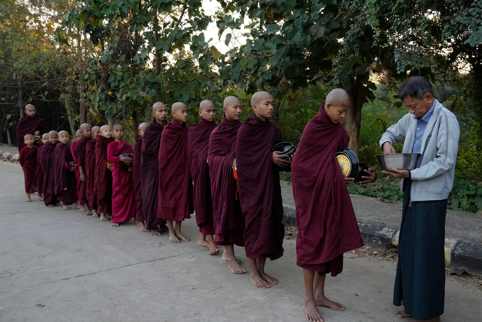 A Buddhist monk receives alms from a devotee Saturday, Feb. 1, 2025, in Naypyitaw, Myanmar. (AP Photo/Aung Shine Oo)