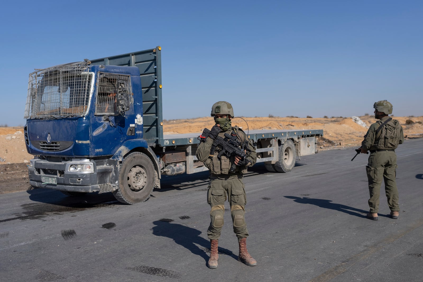 Israeli soldiers stand guard on the Palestinian side of the Kerem Shalom crossing as reporters tour the area where aid is awaiting pickup in the Gaza Strip, Thursday, Dec. 19, 2024. (AP Photo/Ohad Zwigenberg)