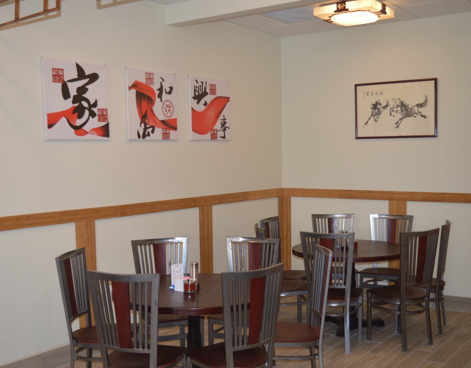 The round tables popular with patrons in the old Phan Shin building return to the new facility in a back corner affording friends to meet for food and conversation with a bit of privacy. The three-paneled sign means harmony in the family. 