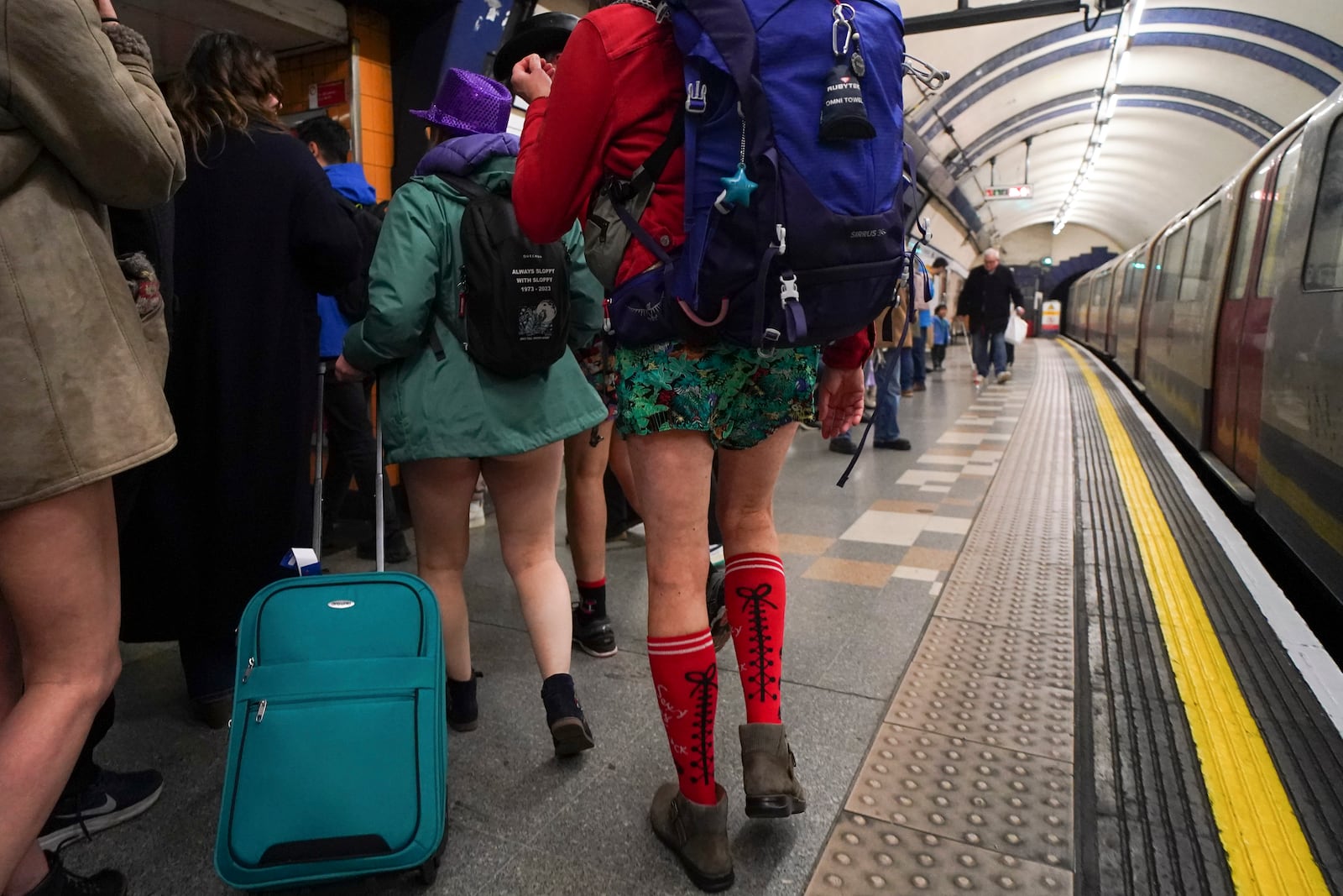 People walk along an underground station's platform as they take part in the annual event "No Trousers Tube Ride" in London, Sunday, Jan. 12, 2025. (AP Photo/Alberto Pezzali)