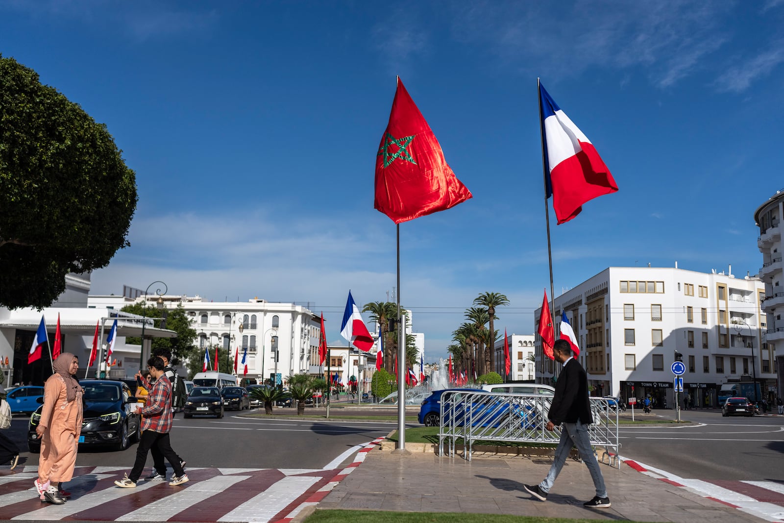 People walk past Moroccan and French flags on Mohammed V avenue ahead of French president Emmanuel Macron official visit to Morocco, in the capital Rabat, Monday, Oct. 28, 2024. (AP Photo/Mosa'ab Elshamy)