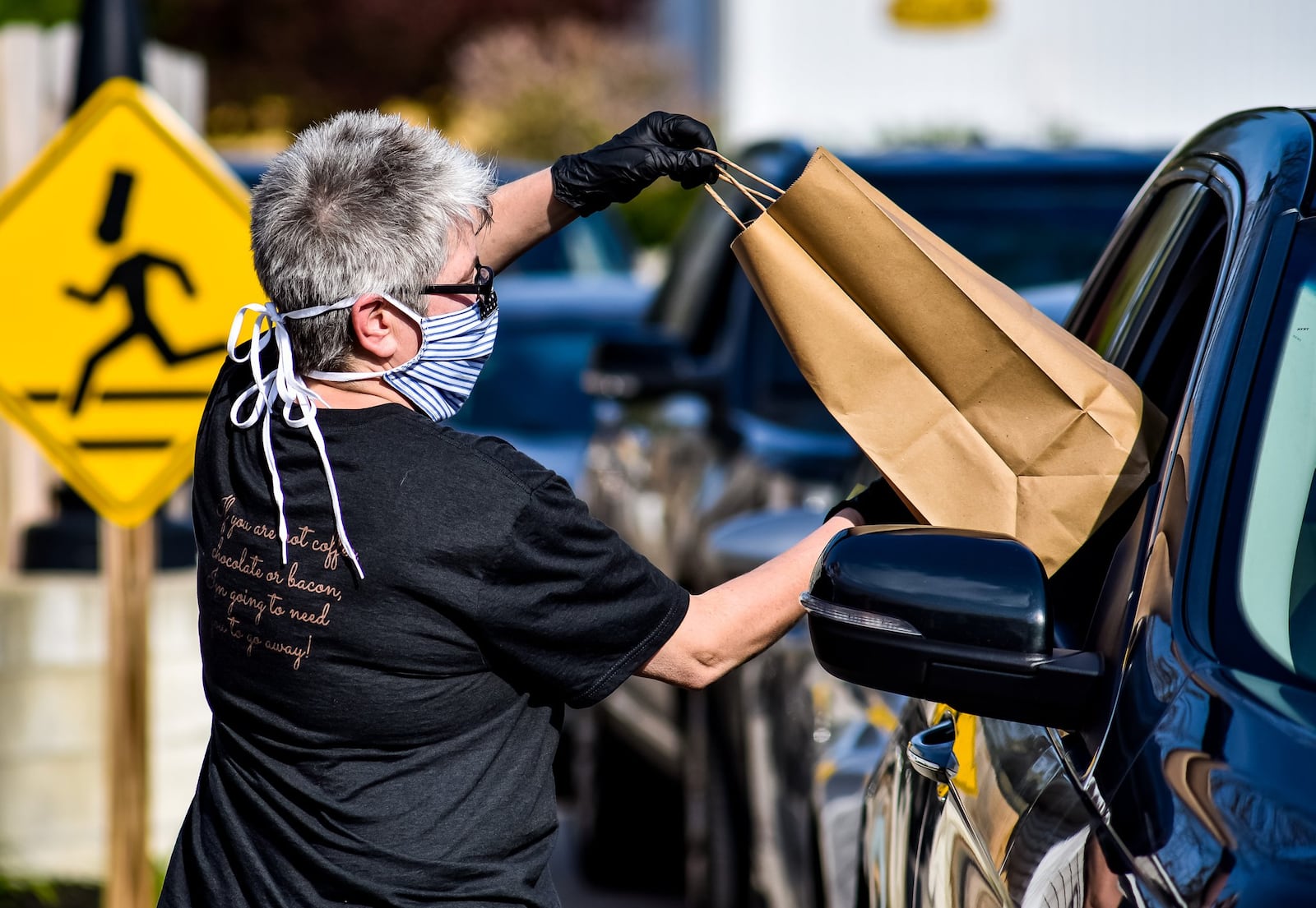 Lynnette Witsken wear masks and gloves she takes and delivers curbside orders at Cozy’s restaurant Tuesday, April 28, 2020 on Cincinnati Dayton Road in Liberty Township. Cozy’s is trying something different on Tuesdays and Thursdays and offering a drive-up service that will vary by week. Tuesday’s offering was a grill out theme with burgers, hotdogs and more available. They also had margaritas to-go for sale. Cozy’s offers carry out food on other days of the week. NICK GRAHAM / STAFF