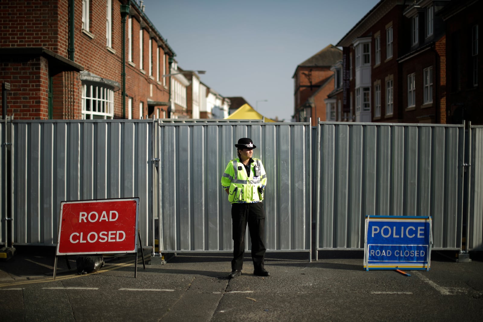 FILE - A police officer guards metal fencing erected on the end of Rollestone Street, the location of the John Baker House for homeless people, in Salisbury, England, Thursday, July 5, 2018. (AP Photo/Matt Dunham, File)