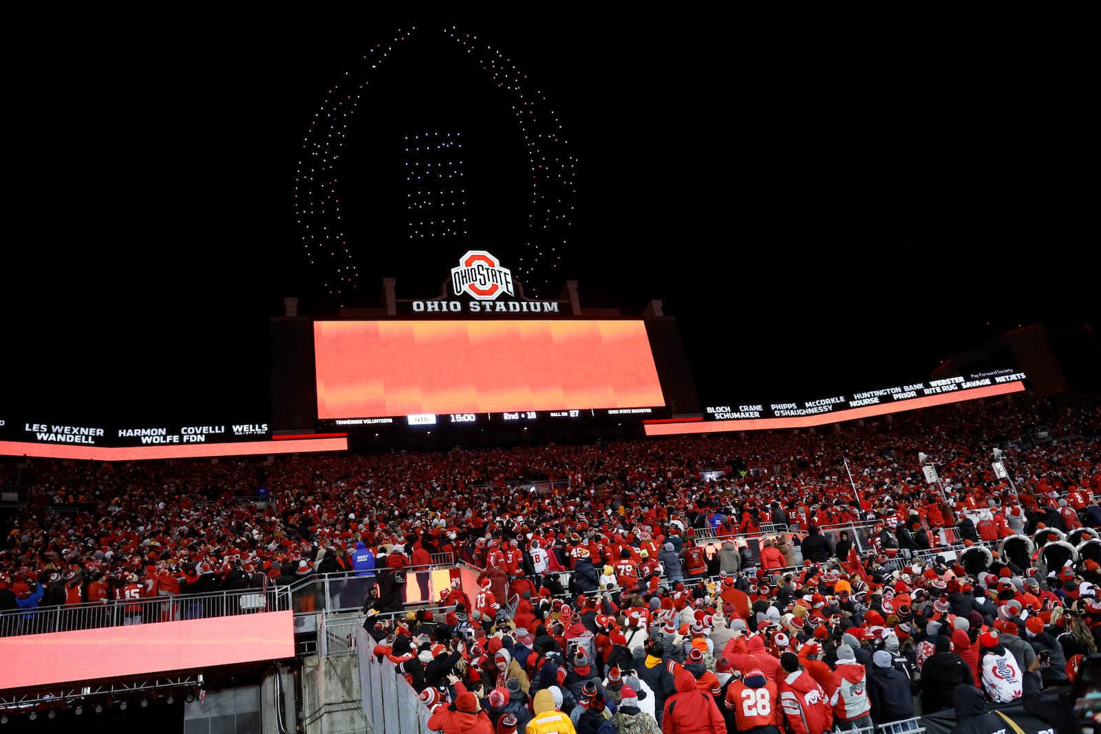 Fans watch a drone show displaying the CFP logo above Ohio Stadium during the second half in the first round of the College Football Playoff between Ohio State and Tennessee, Saturday, Dec. 21, 2024, in Columbus, Ohio. (AP Photo/Jay LaPrete)