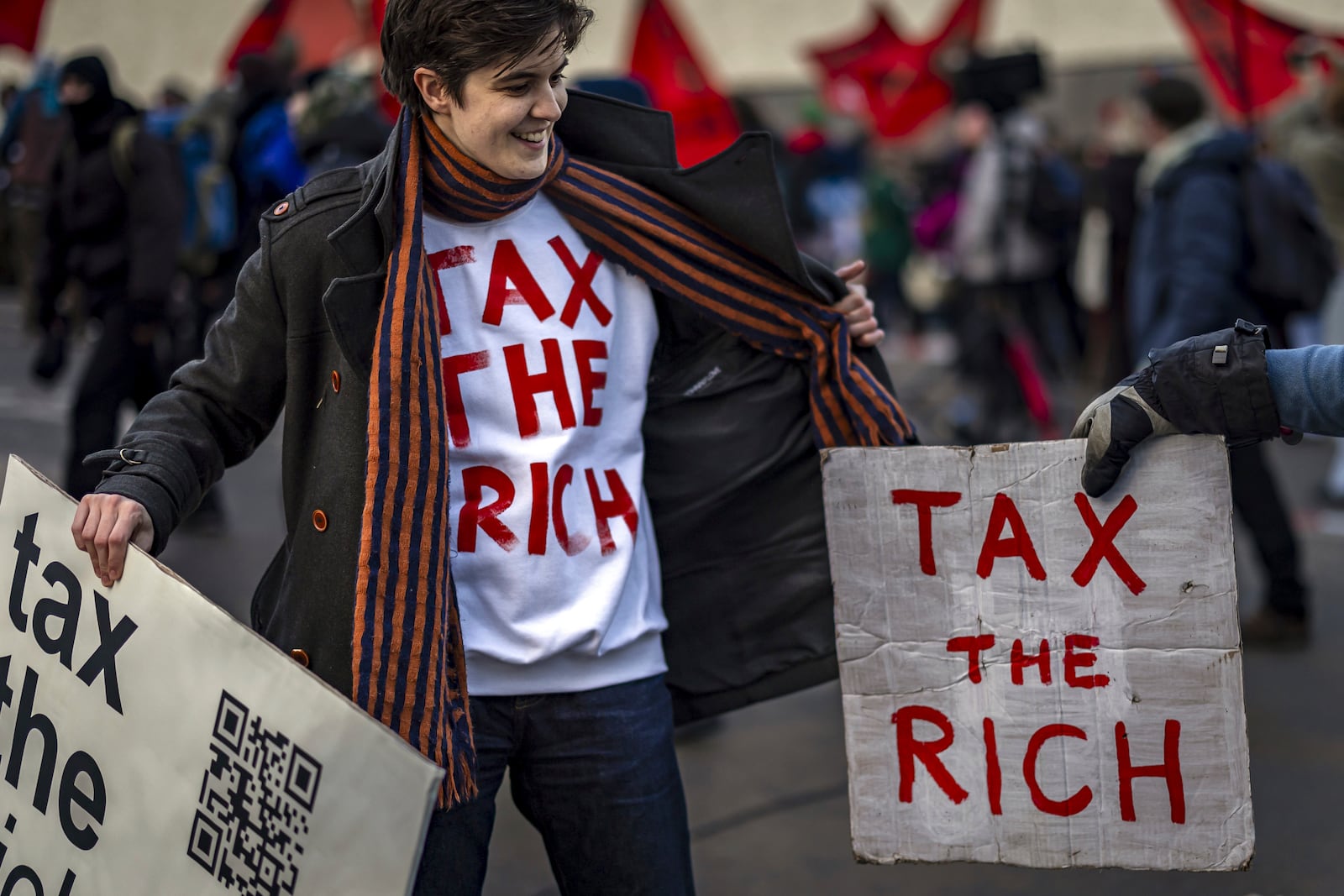 Activist Marlene Engelhorn holds banners during a protest at the Meeting of World Economic Forum in Davos, Switzerland, Thursday, Jan. 23, 2025. (Michael Buholzer/Keystone via AP)