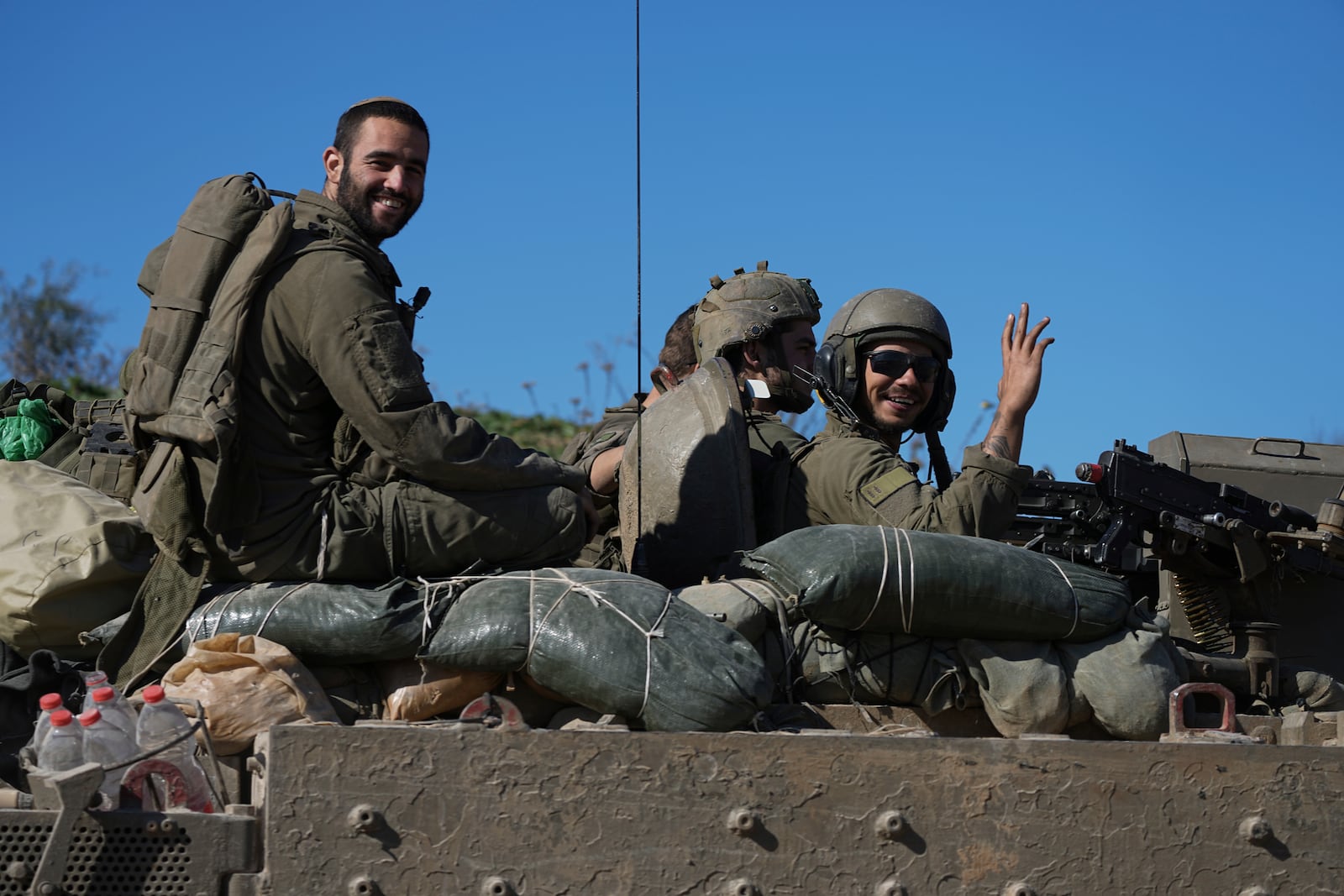 FILE - Israeli soldiers wave to the camera from an APC as they cross from the Gaza Strip into Israel, Saturday, Jan. 18, 2025. (AP Photo/Tsafrir Abayov, File)