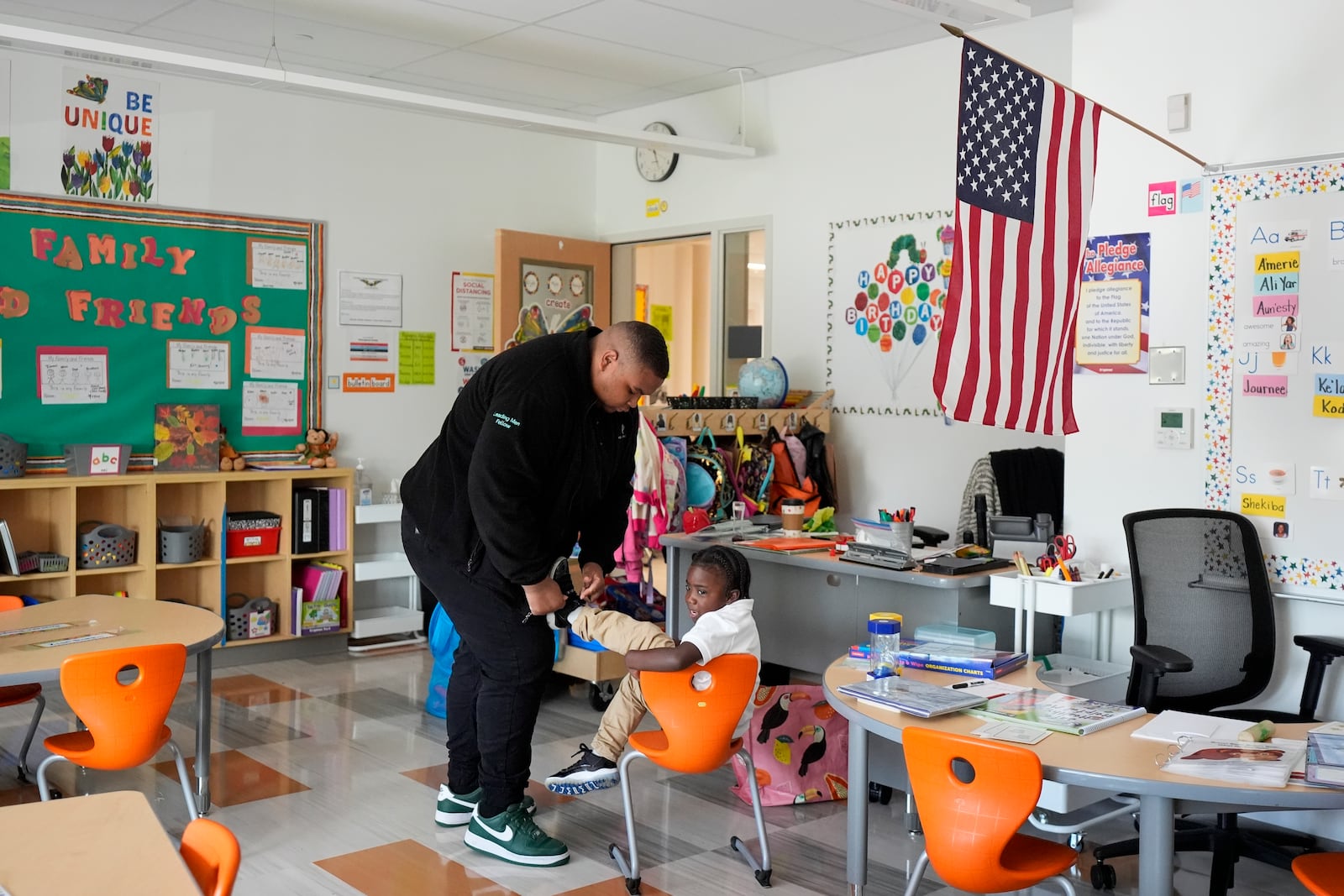 Leading Men fellow Davontez Johnson, right, ties preschooler Kodi's shoes, Thursday, Oct. 3, 2024, at Dorothy I. Height Elementary School in Baltimore. (AP Photo/Stephanie Scarbrough)