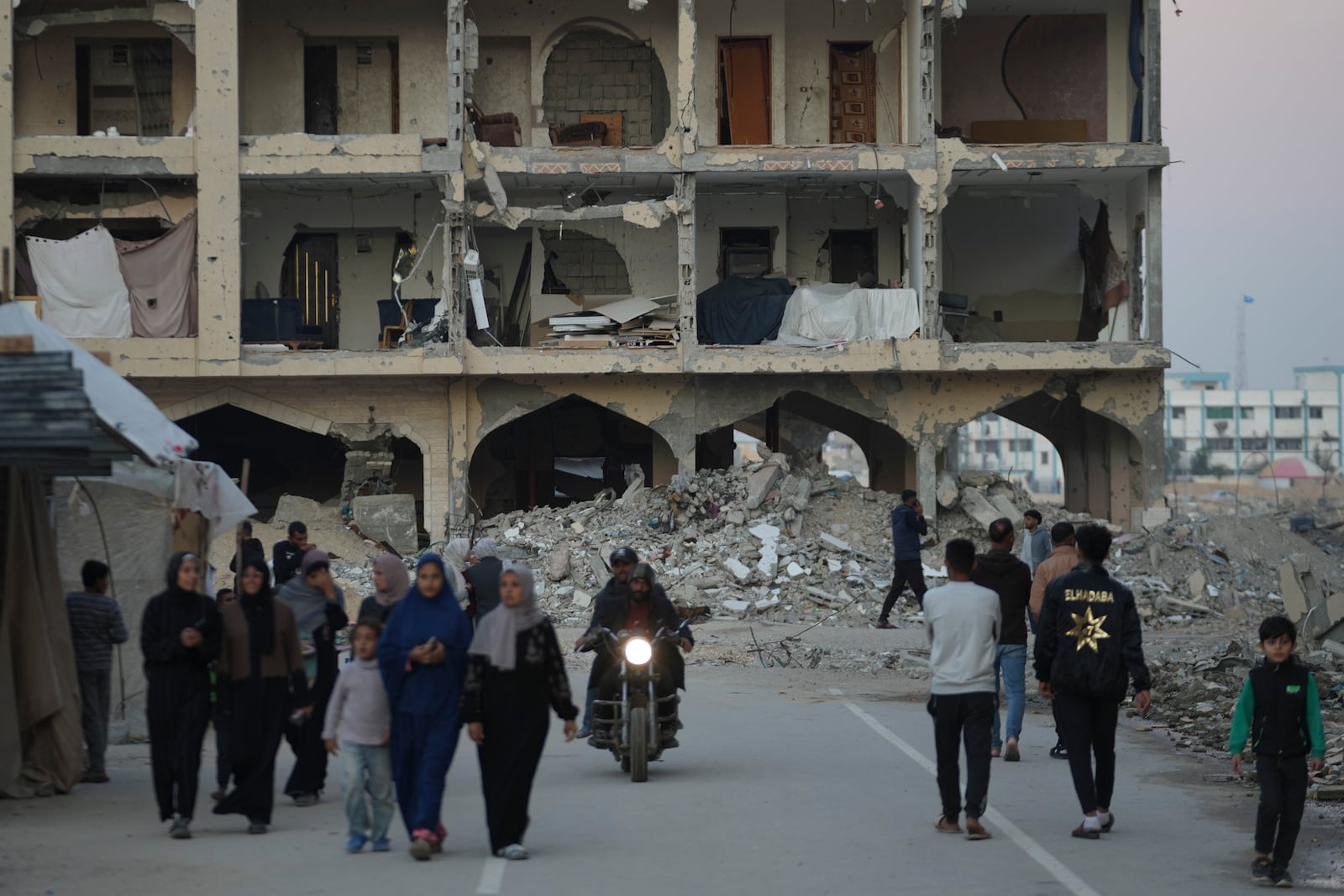 Palestinian walk past destroyed building at a neighbourhood in Khan Younis, Gaza Strip, Sunday, Dec. 1, 2024. (AP Photo/Abdel Kareem Hana)