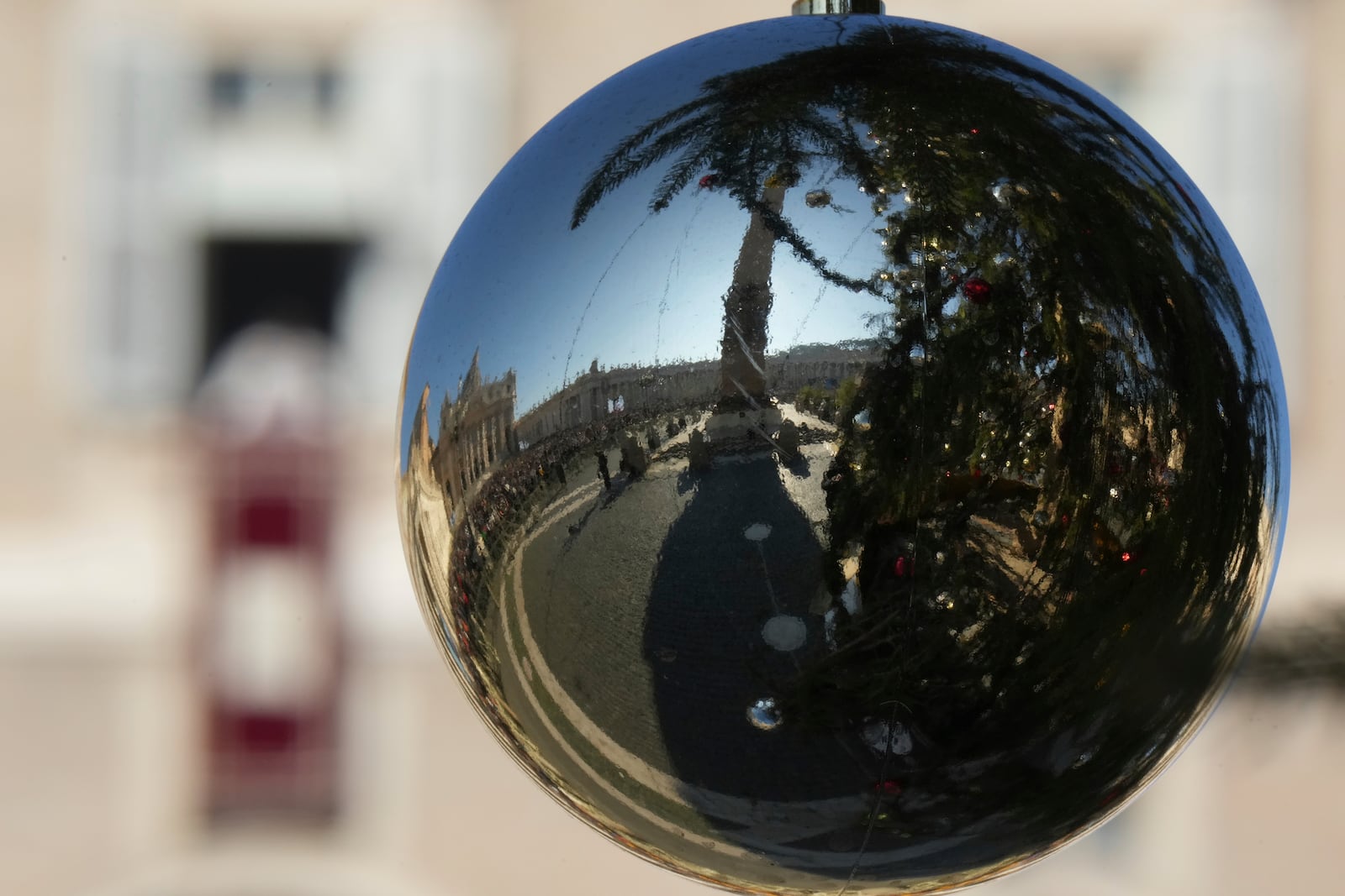 A Christmas tree decoration reflects St. Peter's Square at The Vatican when Pope Francis appeared at his studio's window overlooking the square to bless pilgrims and faithful after presiding over a mass in St. Peter's Basilica on New Year's Day, Wednesday, Jan. 1, 2025. (AP Photo/Andrew Medichini)