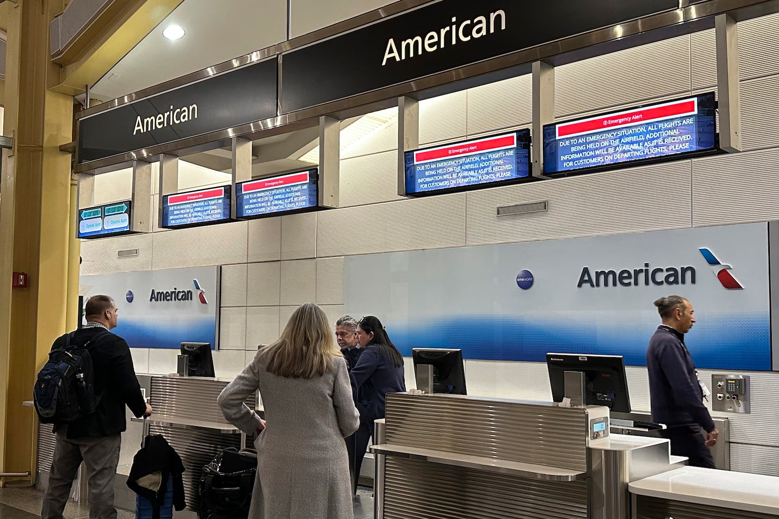 Signs display an "Emergency Alert" above an American Airlines counter in the terminal at Ronald Reagan Washington National Airport, Wednesday night, Jan. 29, 2025, in Arlington, Va. A jet with 60 passengers and four crew members aboard collided with an Army helicopter while landing at Ronald Reagan National Airport near Washington, prompting a large search-and-rescue operation in the nearby Potomac River. (AP Photo/Jeannie Ohm)