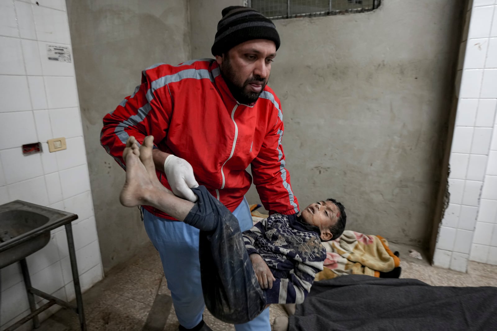 EDS NOTE: GRAPHIC CONTENT - A Palestinian medic holds the body of a child killed in the Israeli bombardment of the Gaza Strip in the morgue at Al-Aqsa Hospital in Deir al-Balah, Thursday, Dec. 19, 2024. (AP Photo/Abdel Kareem Hana)