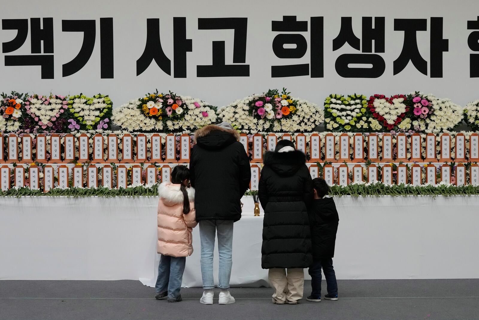 Mourners pray for the victims on a plane fire at a memorial altar at Muan sport park in Muan, South Korea, Monday, Dec. 30, 2024. The sign reads "The victims on a plane." (AP Photo/Ahn Young-joon)