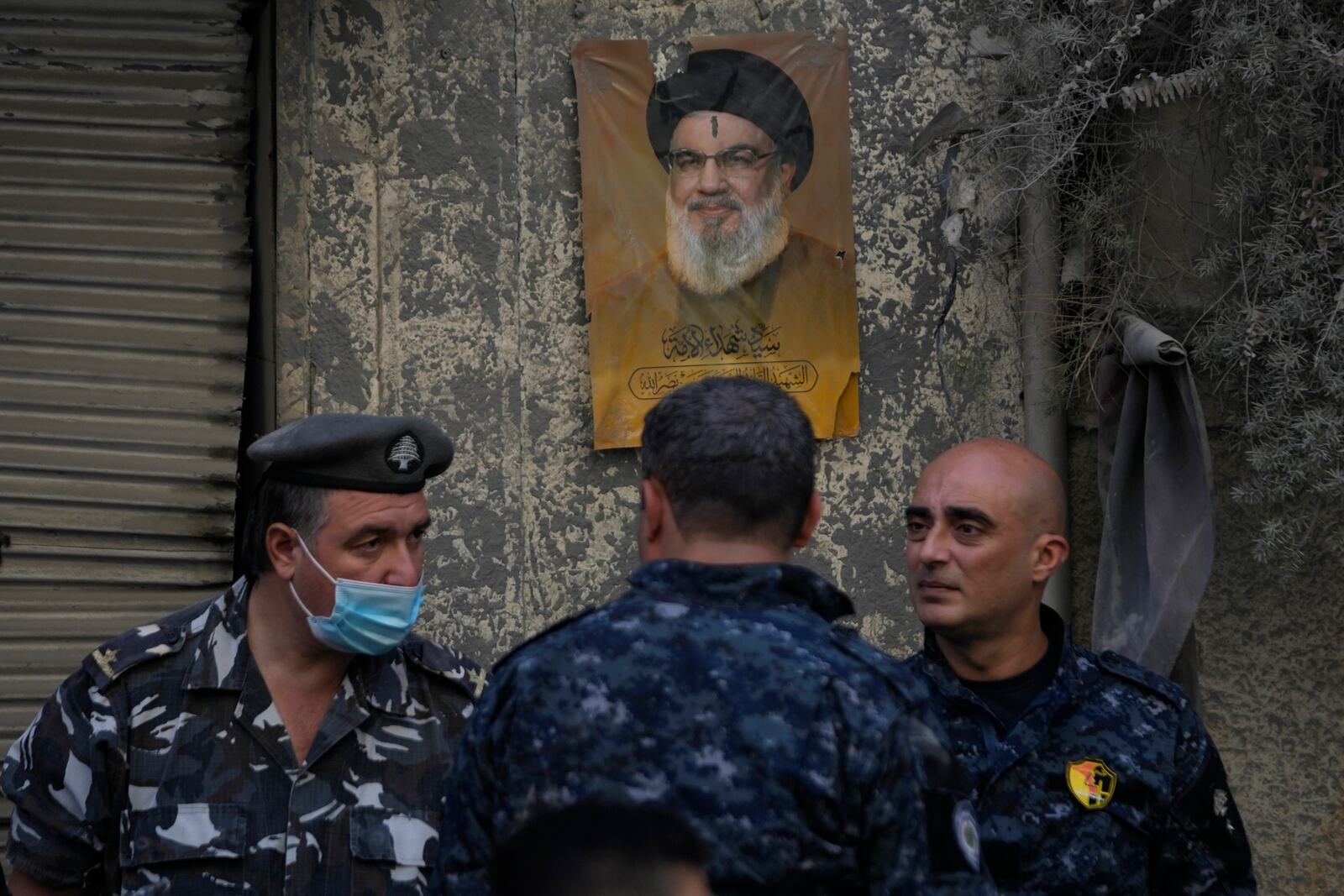 Lebanese police stand in front of a portrait shows the late Hezbollah leader Sayyed Hassan Nasrallah, at the site of an Israeli airstrike that hit central Beirut, Lebanon, Saturday, Nov. 23, 2024. (AP Photo/Hussein Malla)