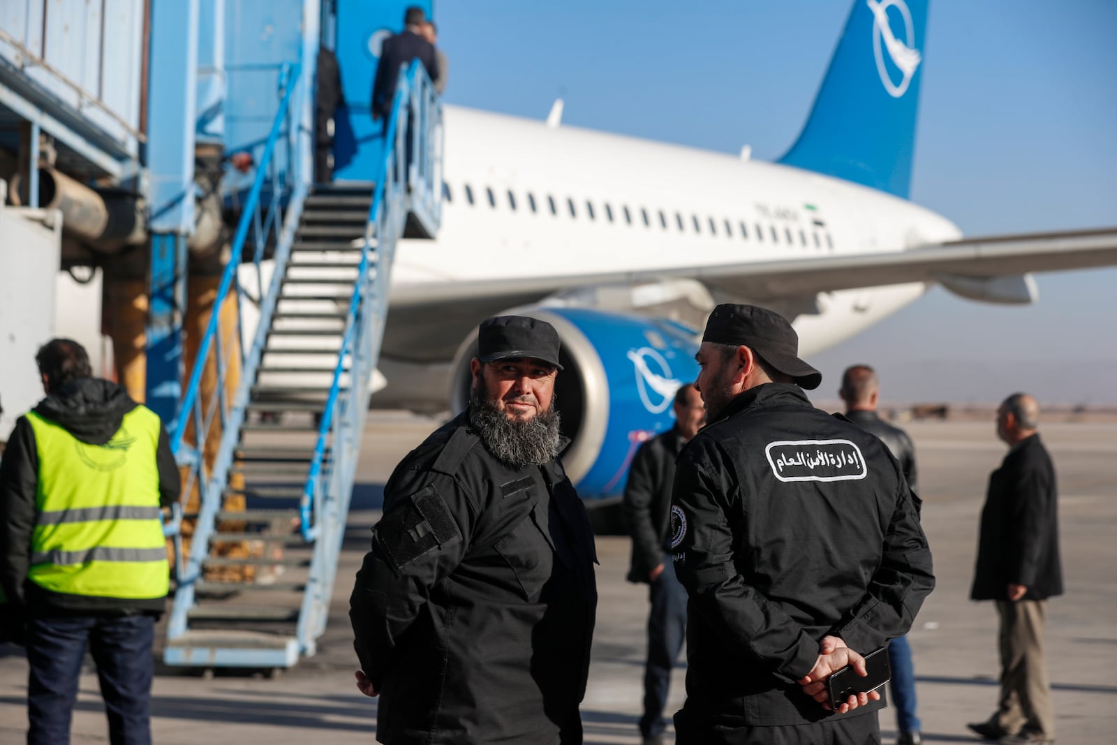 General Security personnel stand next to a Syrian Air airplane ahead of take-off as the airport reopens for internal flights in Damascus, Syria, Wednesday, Dec. 18, 2024. (AP Photo/Omar Sanadiki)