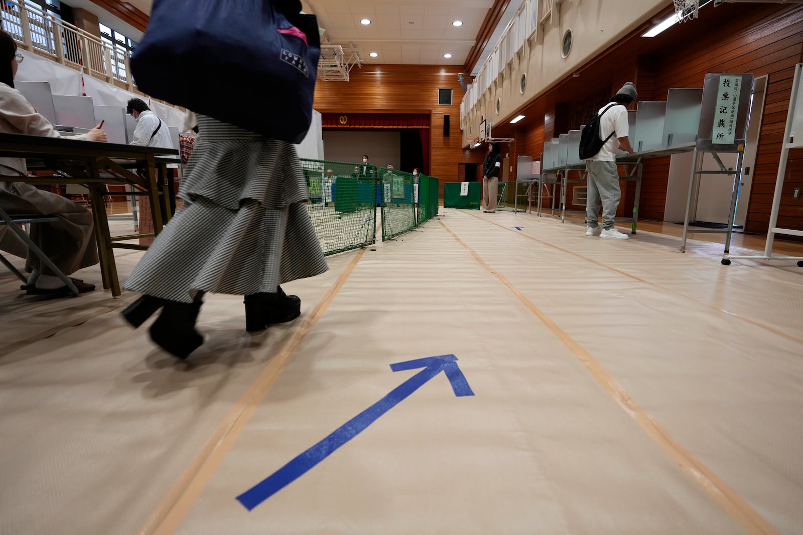 A woman walks towards voting booths at a polling station for Japan's lower house election in Tokyo, Japan, Sunday, Oct. 27, 2024. (AP Photo/Hiro Komae)