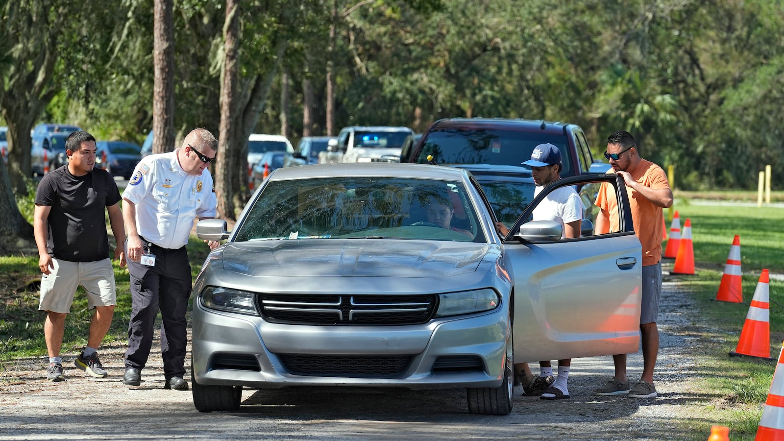 Law enforcement members help a motorist that ran out of fuel while waiting for in line for fuel at a depot Saturday, Oct. 12, 2024, in Plant City, Fla. Gas stations are slow to reopen after the effects of Hurricane Milton. (AP Photo/Chris O'Meara)