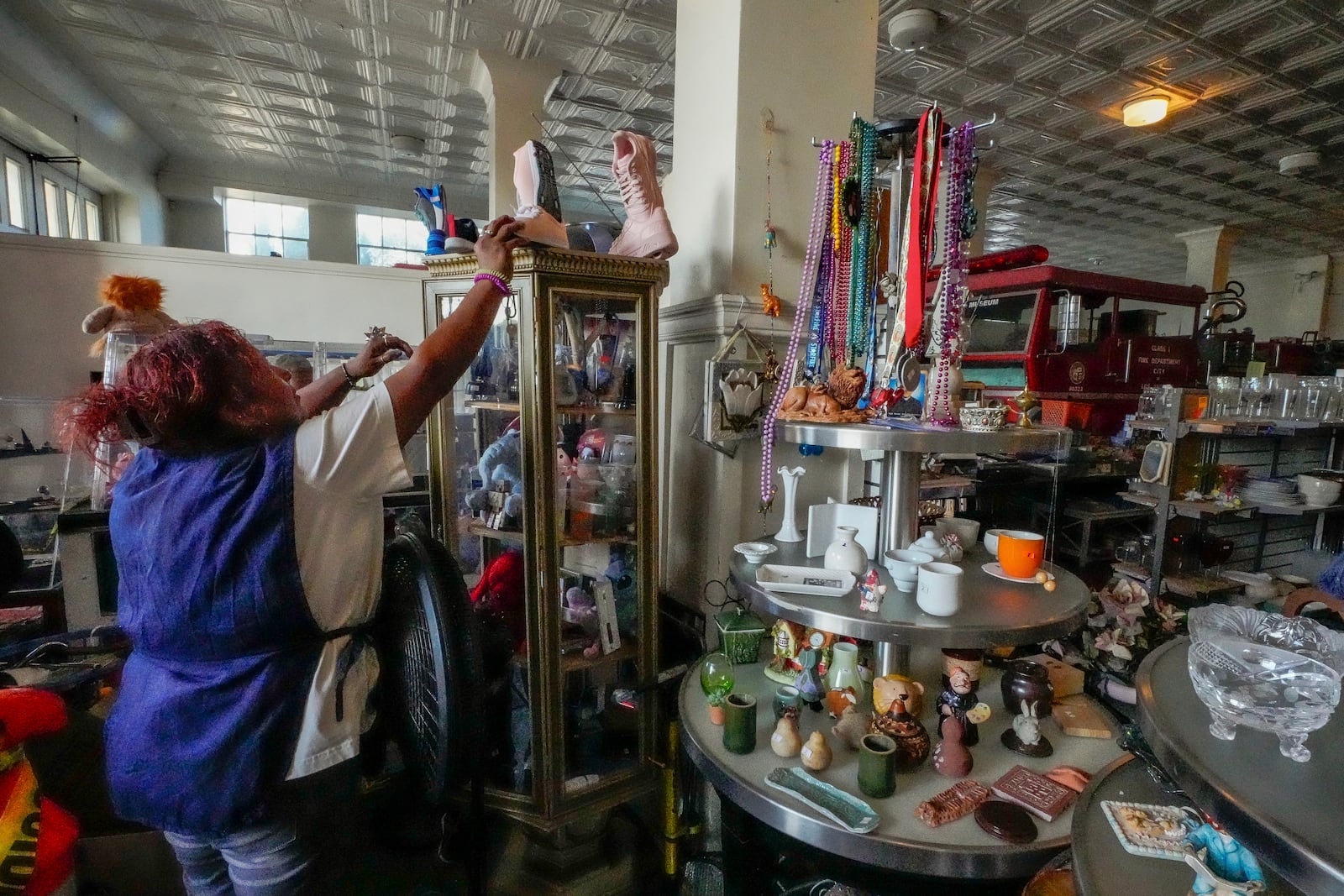 Employee Marylin Moreno, originally from El Salvador, a minimum wage earner, grabs a pair of booths for a client at community thrift store in Los Angeles on Oct. 11, 2024. (AP Photo/Damian Dovarganes)