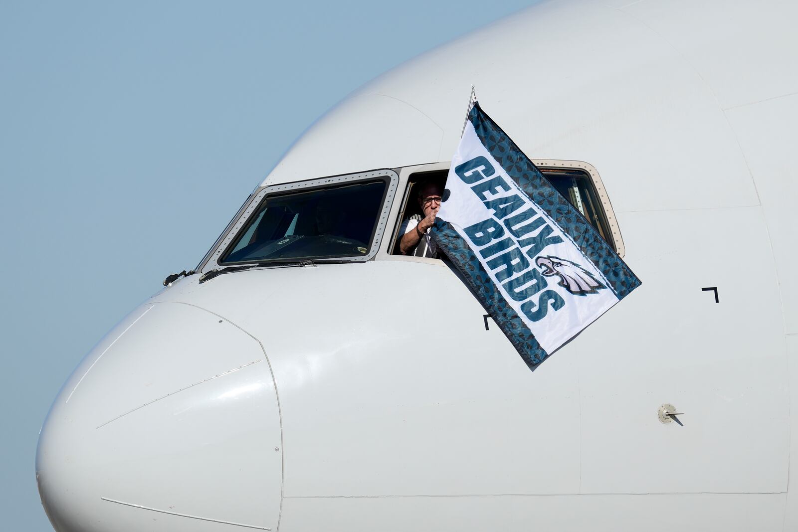 A member of the flight crew waves a Philadelphia Eagles flag after arriving at New Orleans international airport, Sunday, Feb. 2, 2025, in Kenner, La. ahead of the NFL Super Bowl 59 football game between the Philadelphia Eagles and the Kansas City Chiefs. (AP Photo/David J. Phillip)