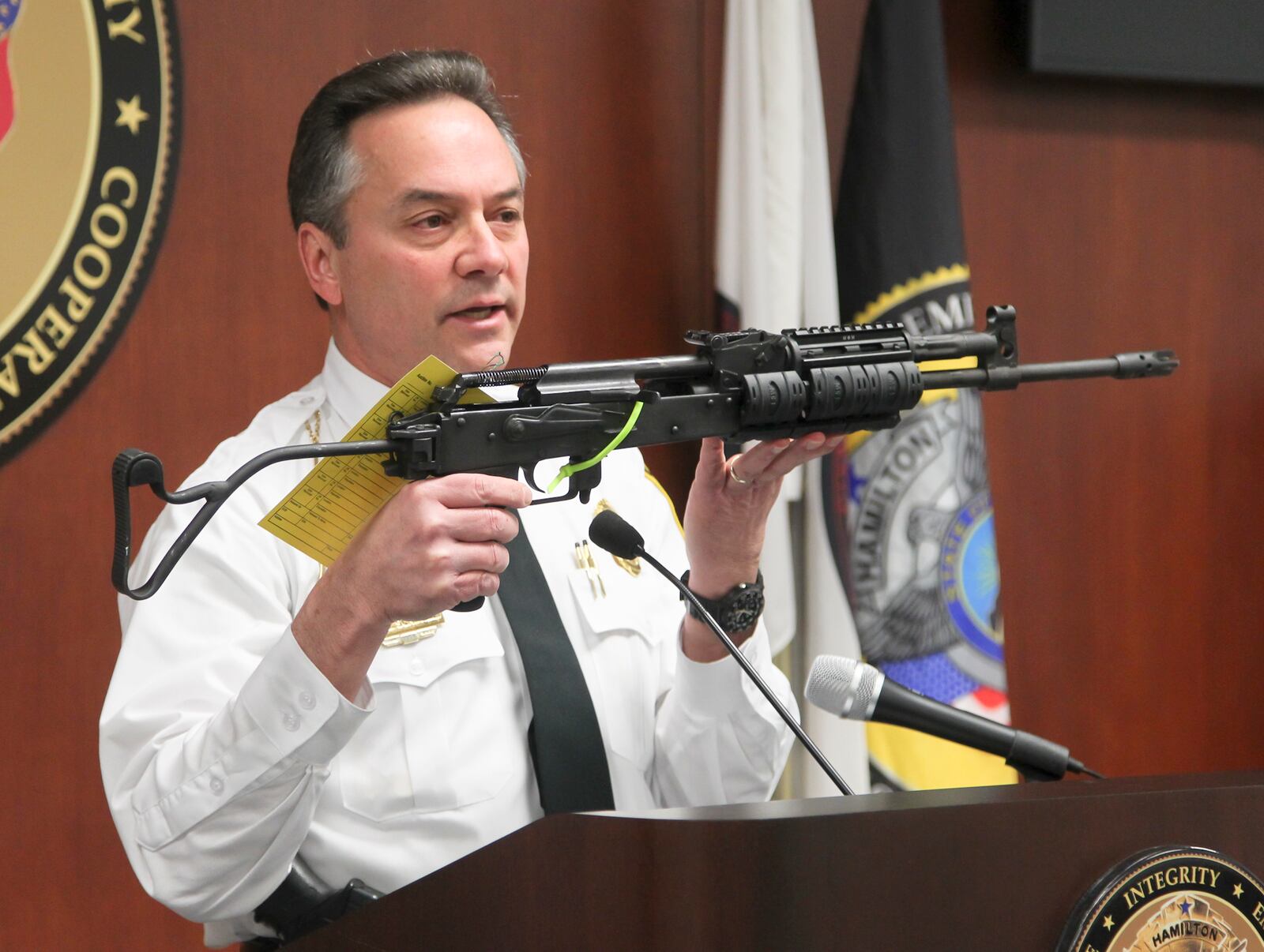 Then-Hamilton Chief of Police Scott Scrimizzi holds the civilian model AK-47 rifle during a press conference at the Police Station, Thursday, Feb. 20, 2014. The rifle was used in the officer involved shooting which occurred in Hamilton, Saturday, Feb. 15, injuring officer Chad Stafford.