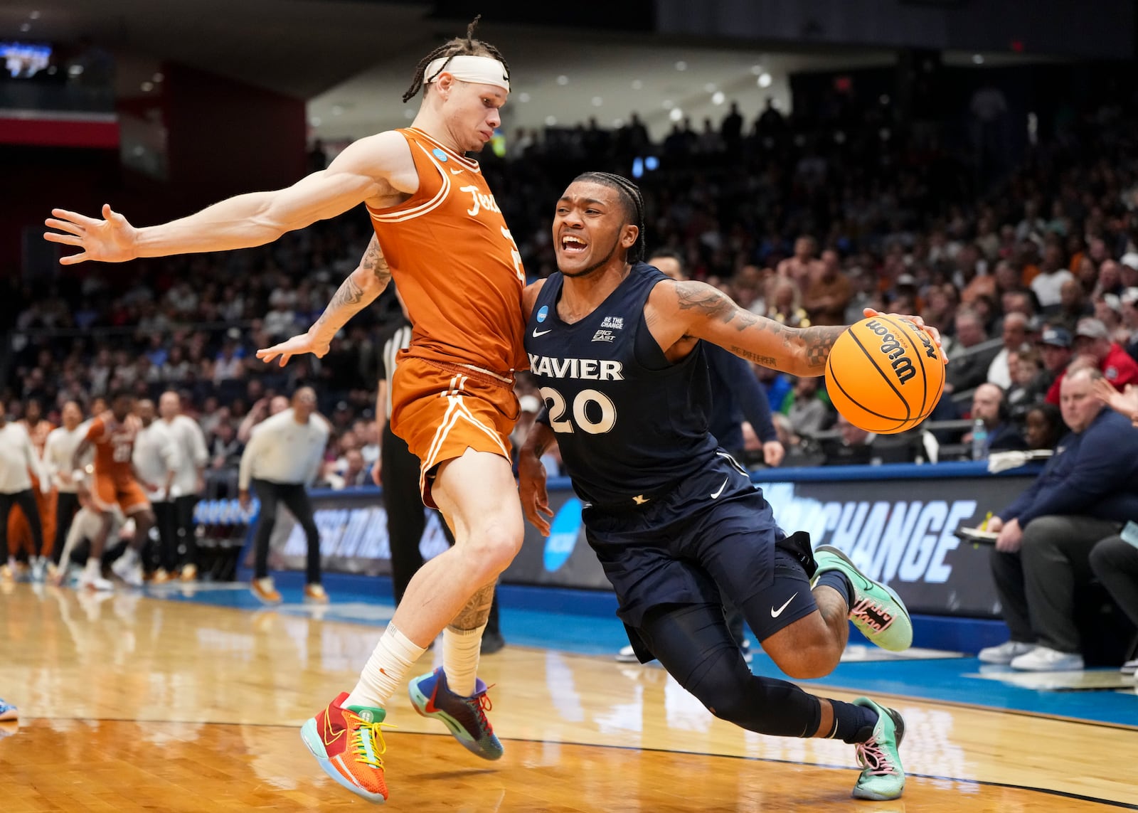 Xavier guard Dayvion McKnight (20) drives against Texas guard Chendall Weaver (2) during the second half of a First Four college basketball game in the NCAA Tournament, Wednesday, March 19, 2025, in Dayton, Ohio. (AP Photo/Jeff Dean)