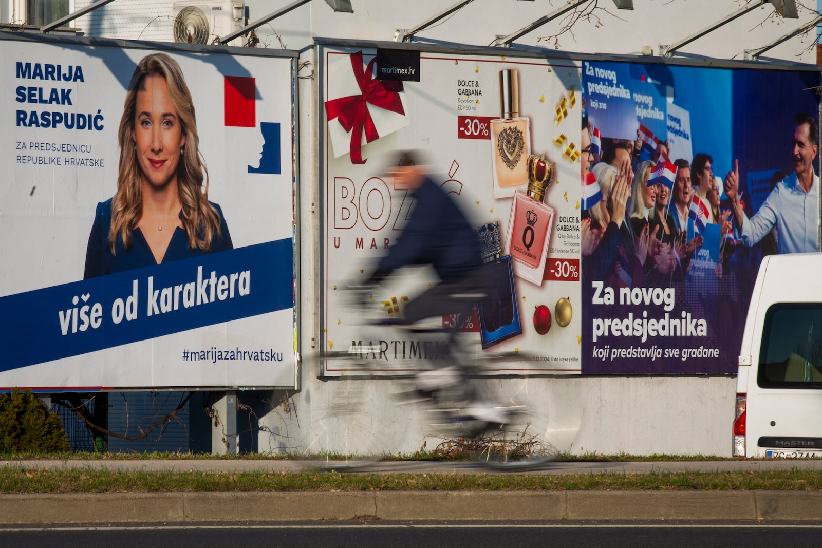 A cyclist rides past campaign posters of presidential candidates Dragan Primorac and Maria Selak Raspudic ahead of the presidential election in Zagreb, Croatia, Thursday, Dec. 26, 2024. (AP Photo)