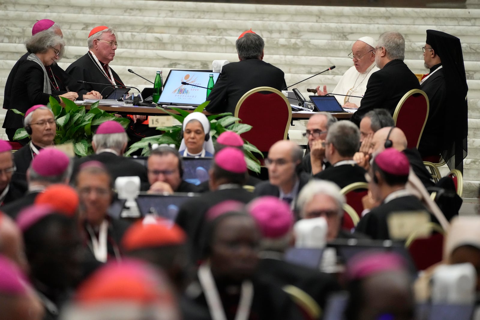 Pope Francis, background right attends the works of the second session of the 16th General Assembly of the Synod of Bishops in the Paul VI hall, at the Vatican, Saturday, Oct. 26, 2024. (AP Photo/Gregorio Borgia)