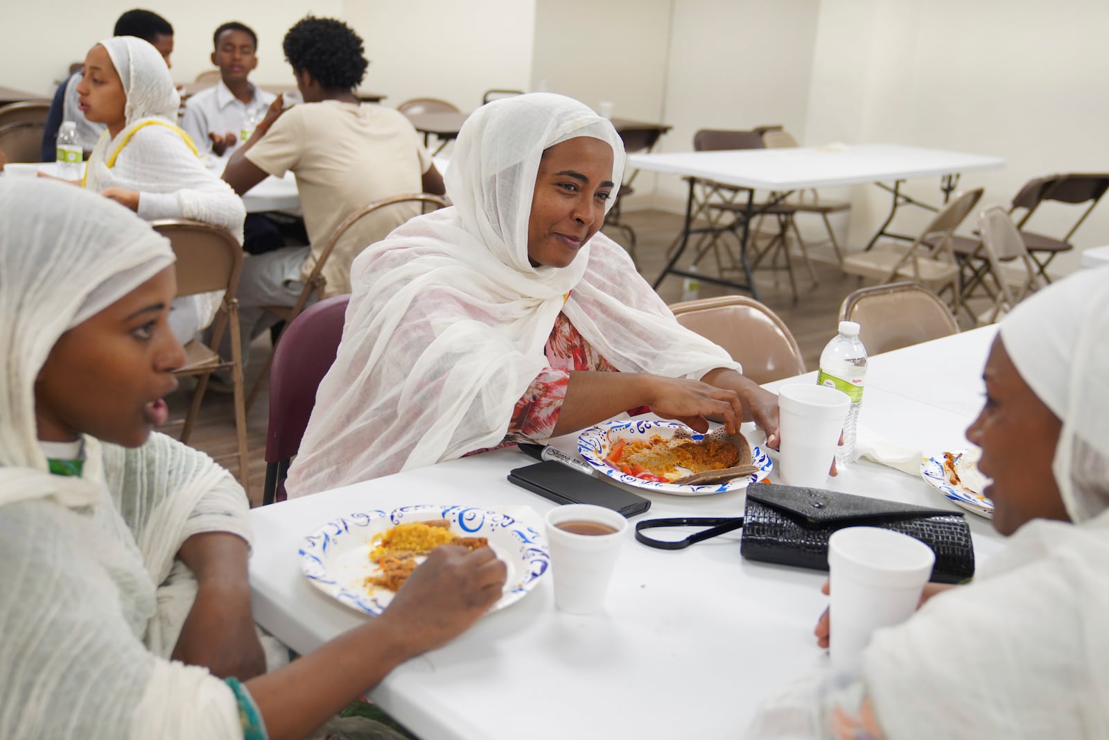 Mintamir Endanew, left, and other women at the Ethiopian Orthodox Tewahedo Church enjoy a post-liturgy lunch of pancake-like injera bread on Sunday, Oct. 20, 2024, in Worthington, Minn. (AP Photo/Jessie Wardarski)