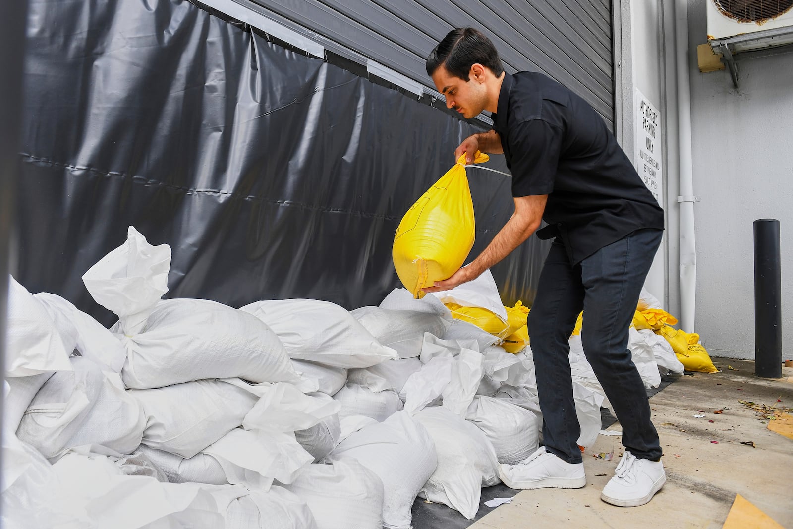 A worker installs sandbags at an engineering business in Brisbane, Australia, Thursday, March 6, 2025. (Jono Searle/AAP Image via AP)