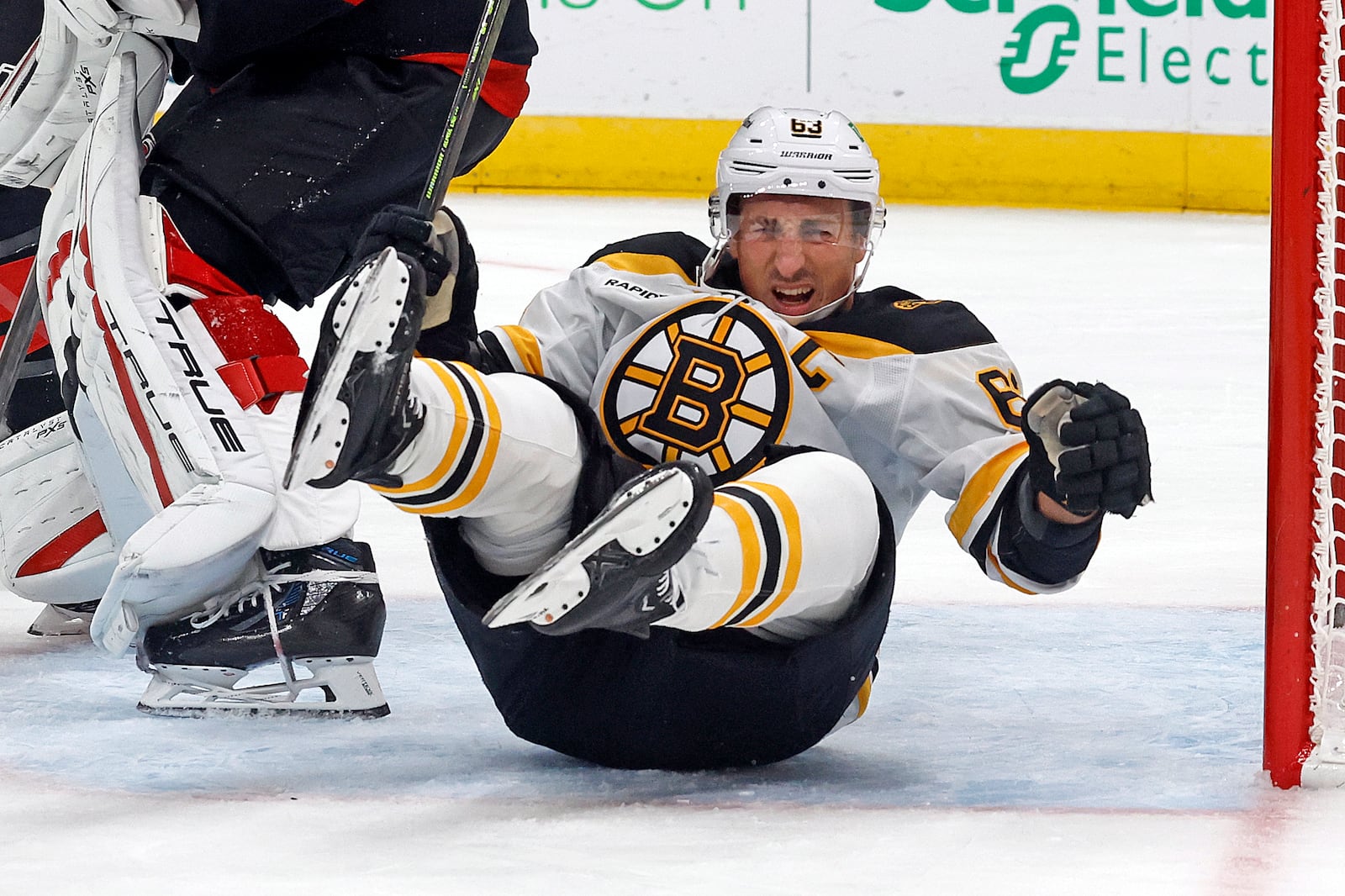 Boston Bruins' Brad Marchand (63) falls in the Carolina Hurricanes crease during the first period of an NHL hockey game in Raleigh, N.C., Thursday, Oct. 31, 2024. (AP Photo/Karl B DeBlaker)