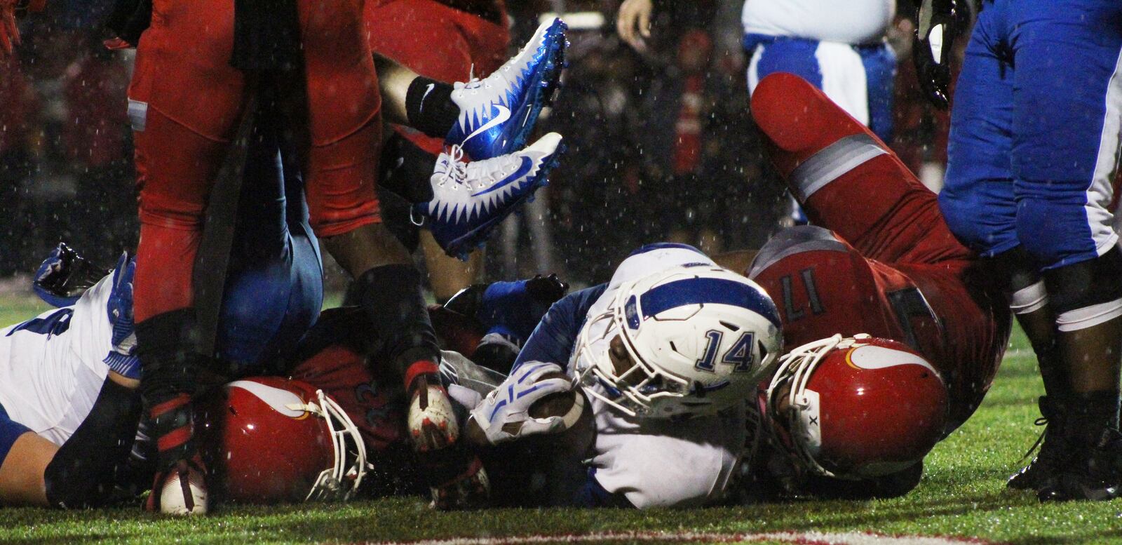 Hamilton’s Kaleb Johnson (14) finds himself at the bottom of a pile at the end of a run Friday night in Sharonville. Visiting Big Blue lost to Princeton 21-20. CONTRIBUTED PHOTO BY ISAIAH MILLER