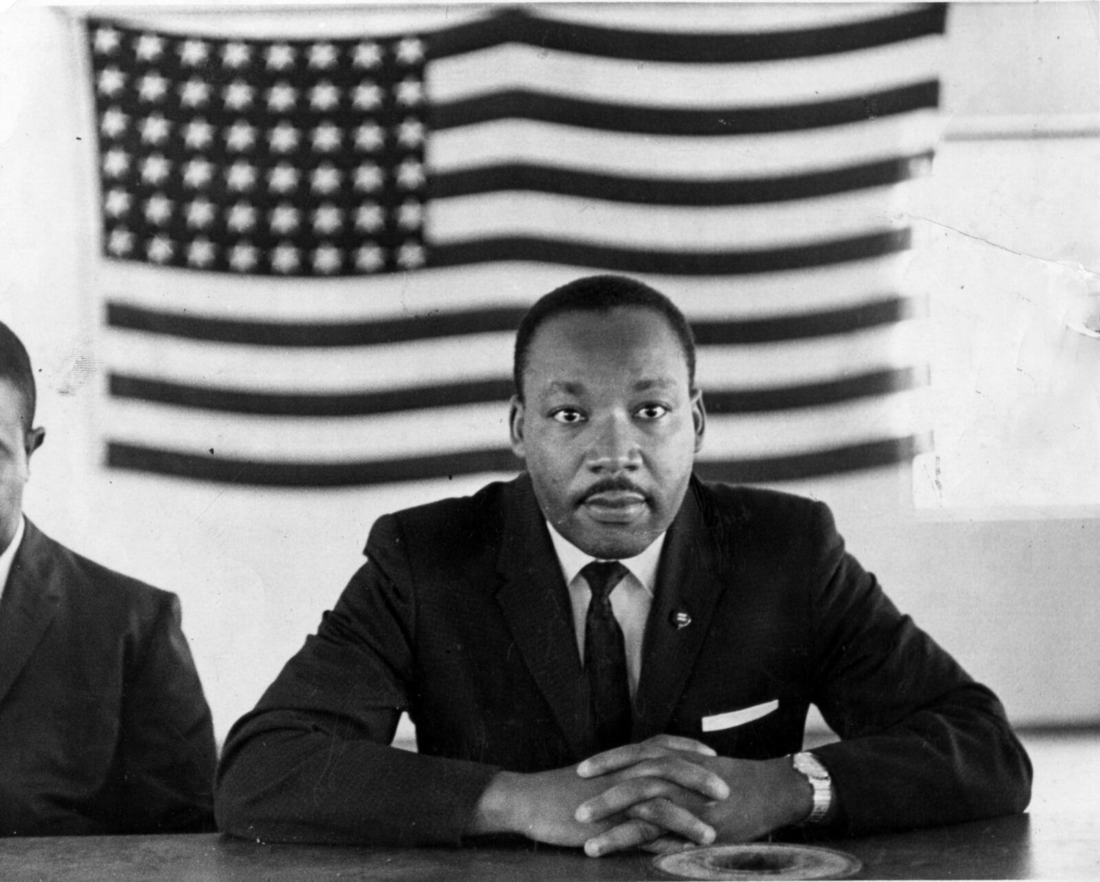 Martin Luther King Jr. sits in front of an American flag during a meeting in St. Augustine, Florida, June 1964. 