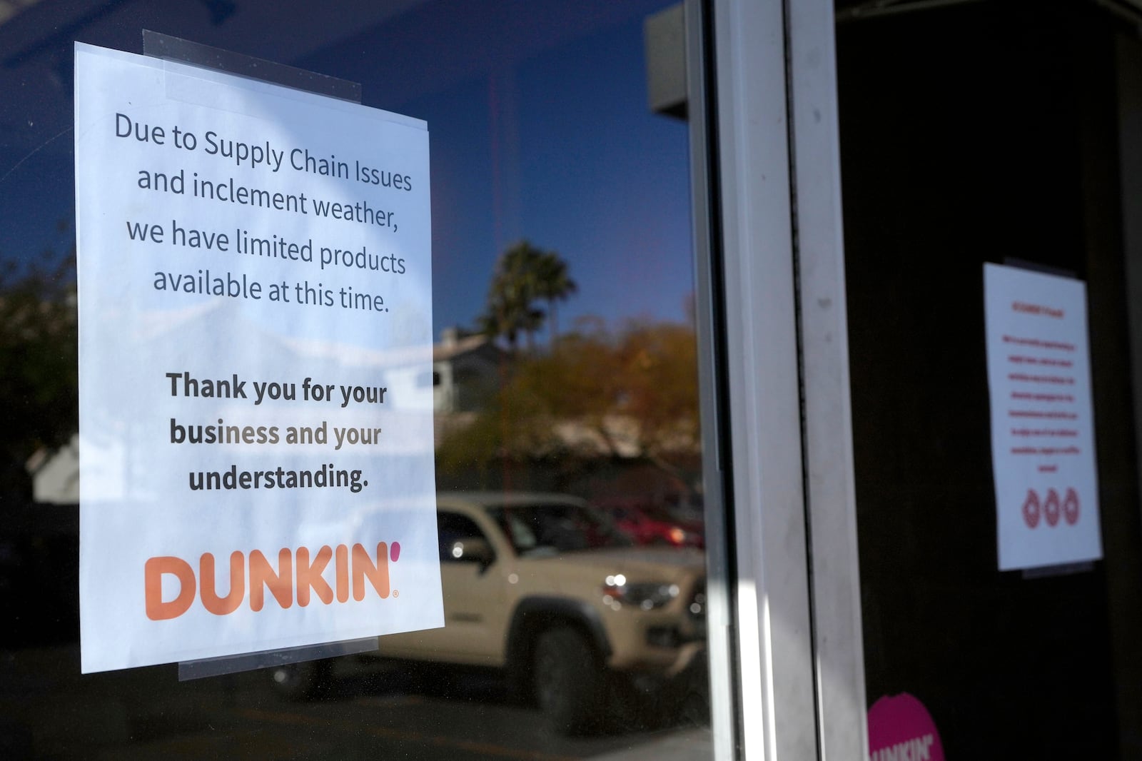 Signs on the doors of a Dunkin' Donuts restaurant explains that customers will find limited doughnut selections for sale Friday, Jan. 10, 2025, in Tempe, Ariz. (AP Photo/Ross D. Franklin)