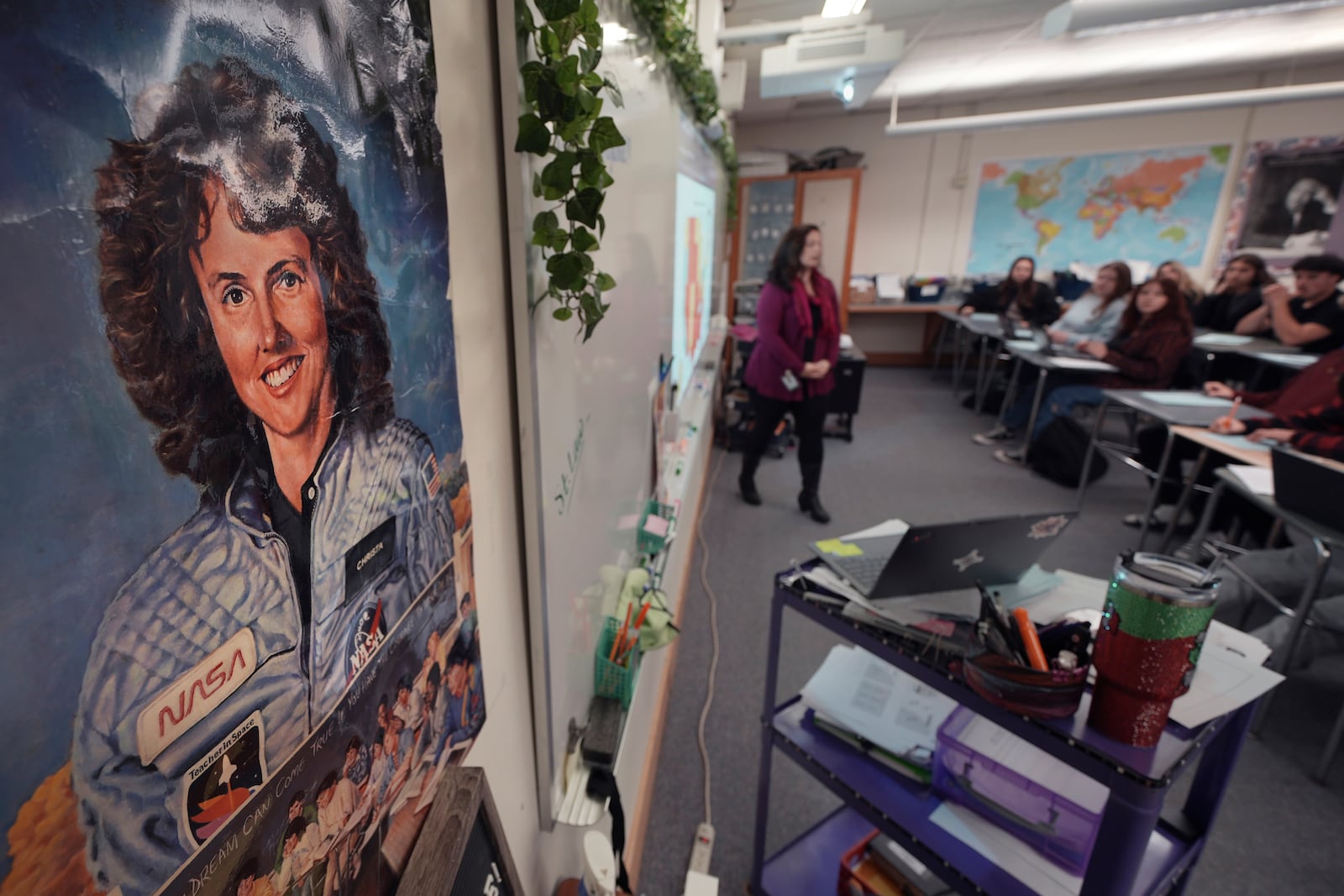 With a poster of NASA's first teacher in space Christa McAuliffe displayed on the wall, teacher Kimberly Bleier instructs her students in one of classrooms where McAuliffe taught at Concord High School, Monday, Dec. 16, 2024, in Concord, N.H. (AP Photo/Charles Krupa)