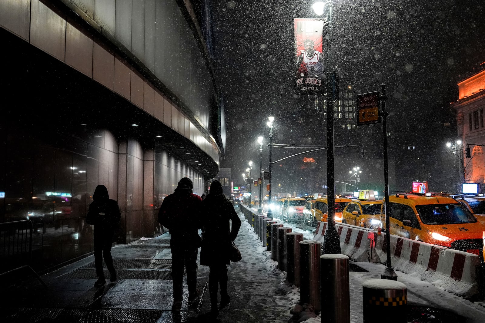 People walk through snow outside Madison Square Garden, Tuesday, Feb. 11, 2025, in New York. (AP Photo/Julia Demaree Nikhinson)