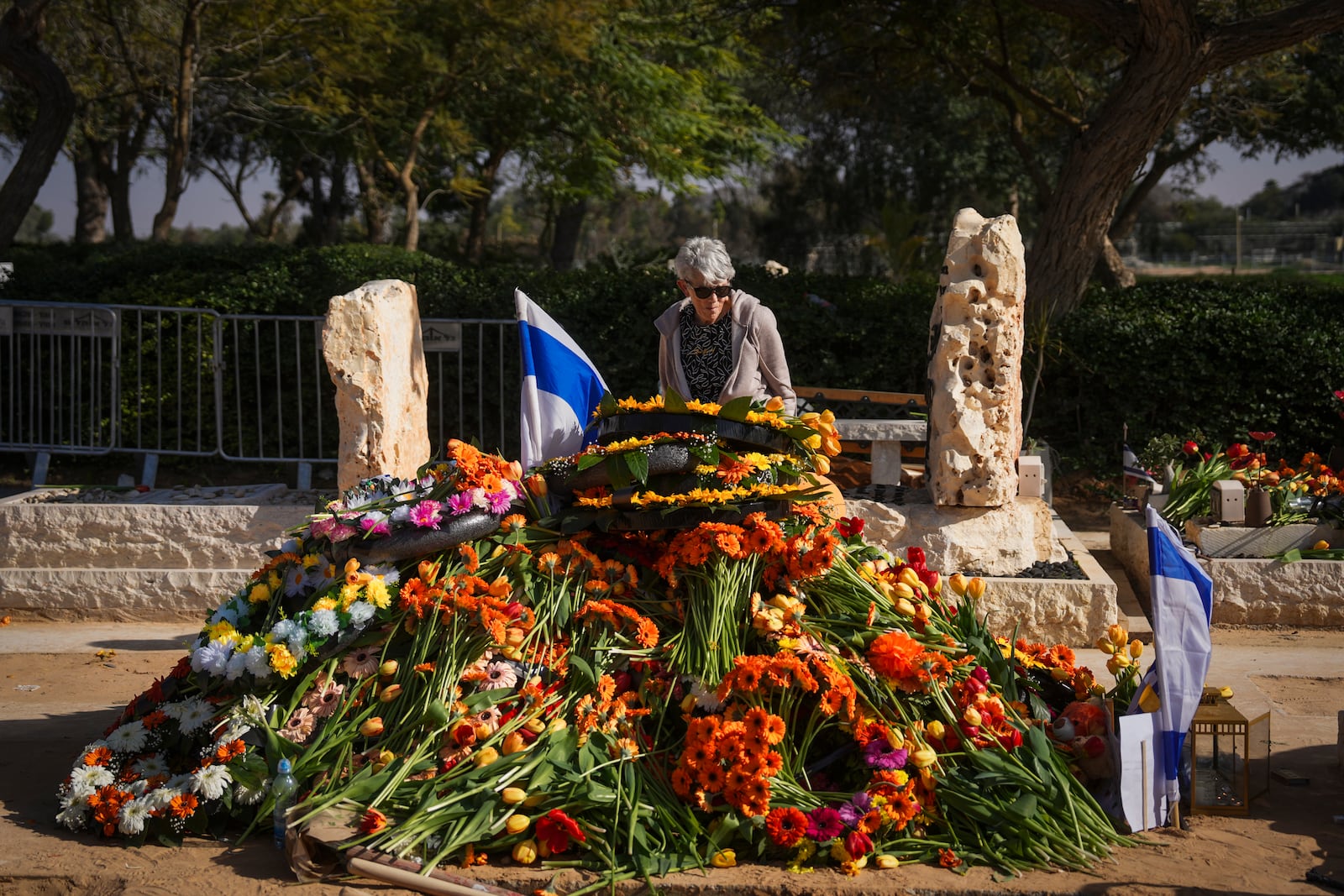 A woman pays tribute at the joint grave of slain hostages Shiri Bibas and her two children, Ariel and Kfir, following their funeral in Tzohar, southern Israel, Wednesday, Feb. 26, 2025. The mother and her two children were abducted by Hamas on Oct. 7, 2023, and their remains were returned from Gaza to Israel last week as part of a ceasefire agreement with Hamas. (AP Photo/Ohad Zwigenberg)