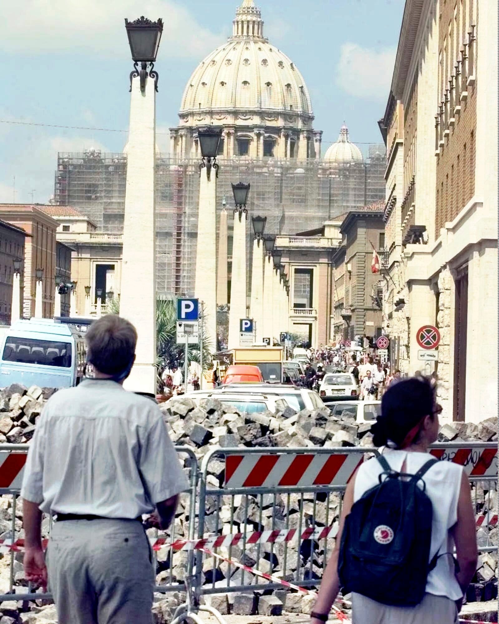 FILE - Tourists approaching the Vatican's St. Peter's Basilica Saturday, July 11, 1998, walk through street works. (AP Photo/Massimo Sambucetti, File)