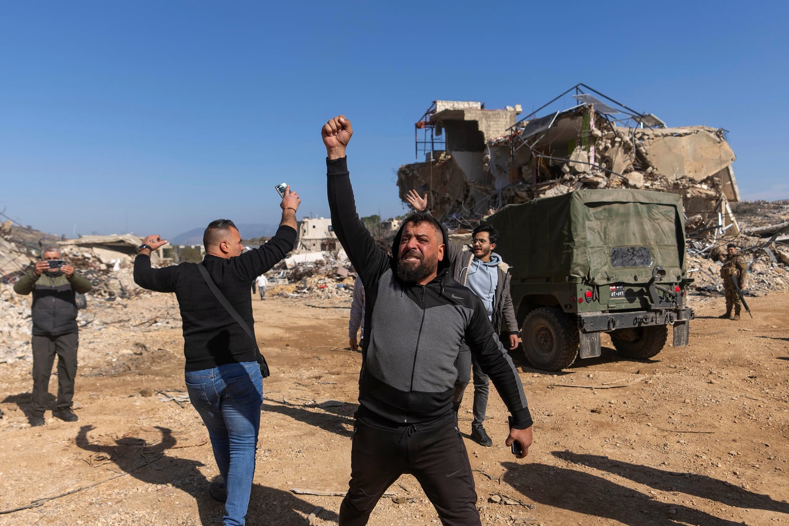 Lebanese men react after they entered their destroyed hometown of Kfar Kila, southern Lebanon, Tuesday, Feb. 18, 2025. (AP Photo/Hassan Ammar)