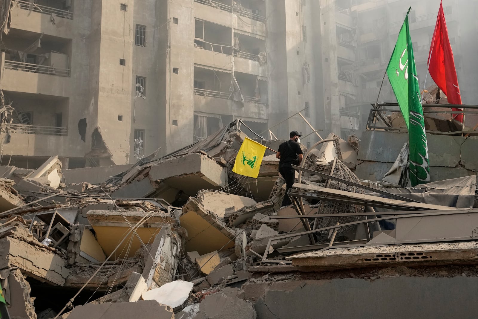 A man carries a Hezbollah flag as he walks on the rubble of his destroyed apartment following an Israeli airstrike in Dahiyeh, Beirut, Lebanon, Friday, Nov. 1, 2024. (AP Photo/Hassan Ammar)