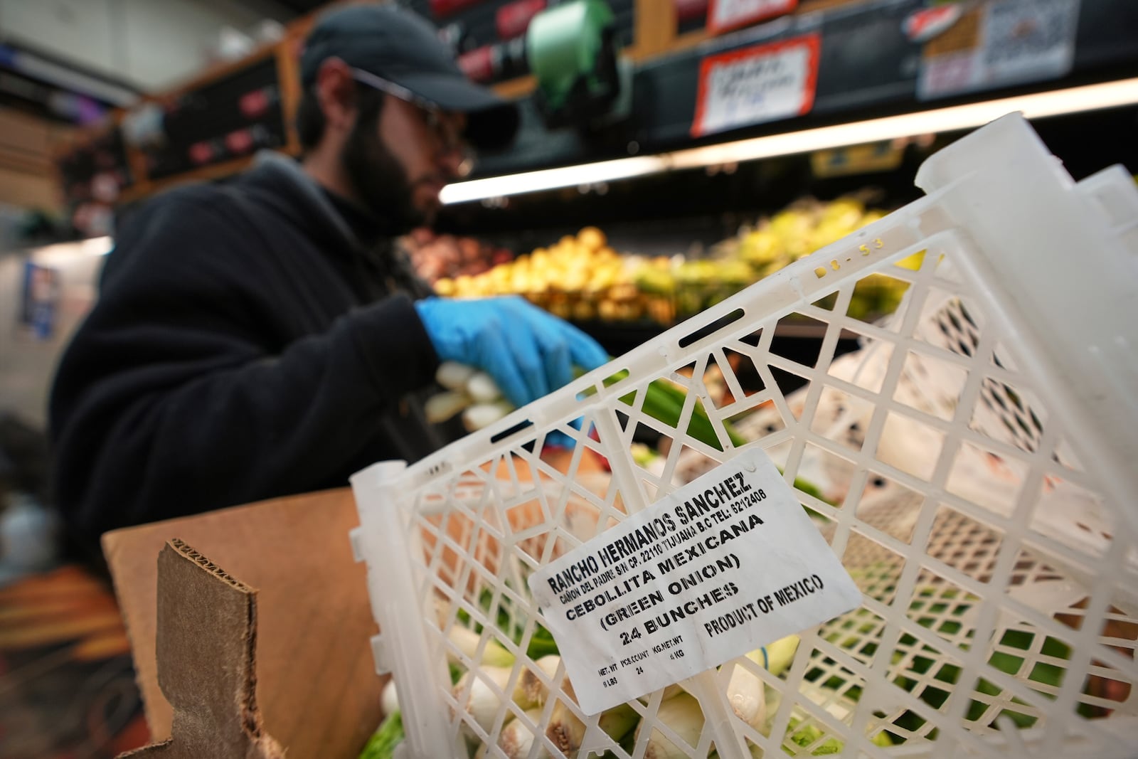 Isaac Arguelles stocks Mexican-grown green onions at a market as tariffs against Mexico go into effect Tuesday, March 4, 2025, in San Diego. (AP Photo/Gregory Bull)