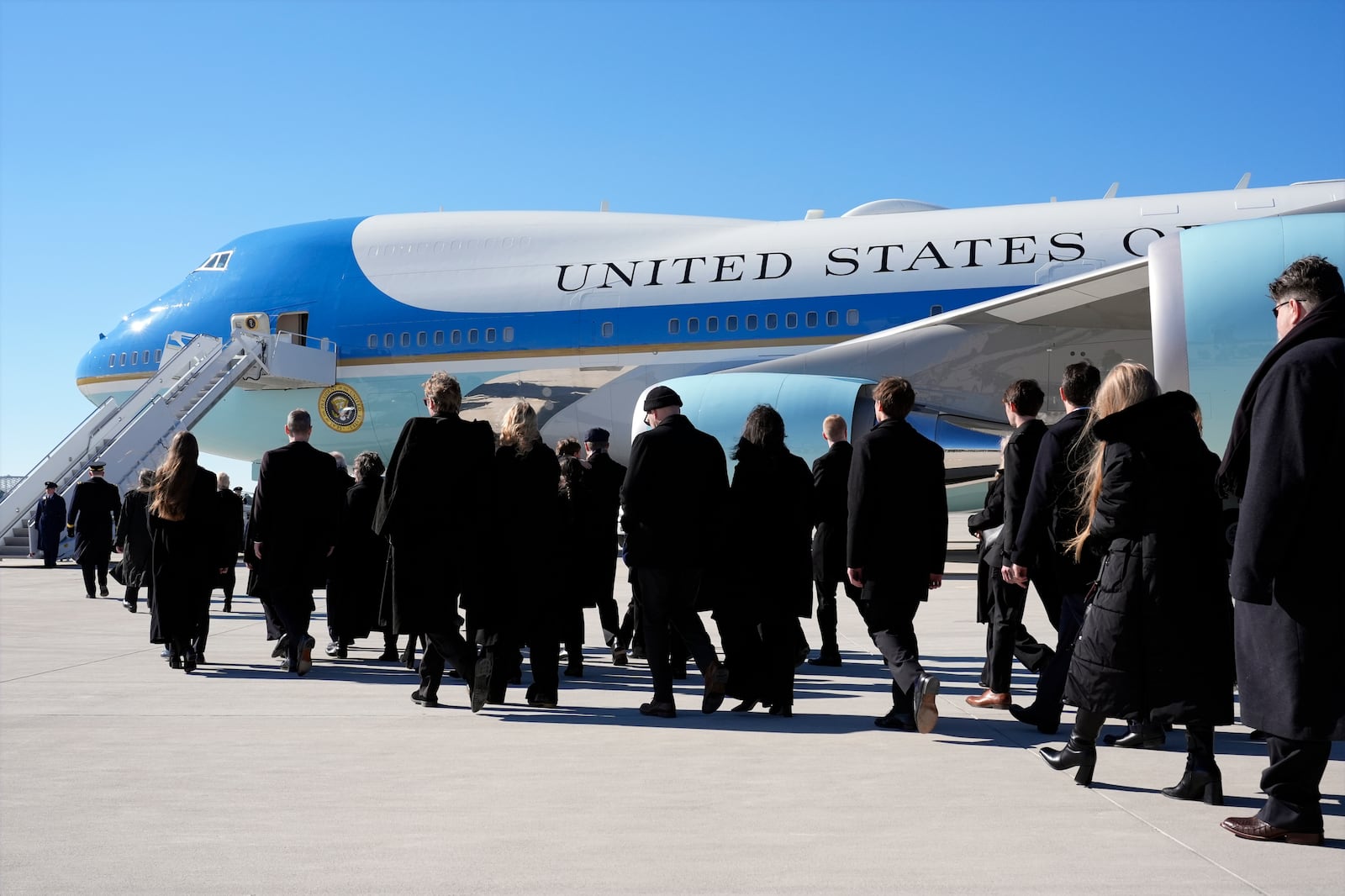 Family members walk to board the plane after the flag-draped casket of former President Jimmy Carter was placed on Special Air Mission 39 at Dobbins Air Reserve Base in Marietta, Ga., Tuesday, Jan. 7, 2025. Carter died Dec. 29 at the age of 100. (AP Photo/Alex Brandon, Pool)