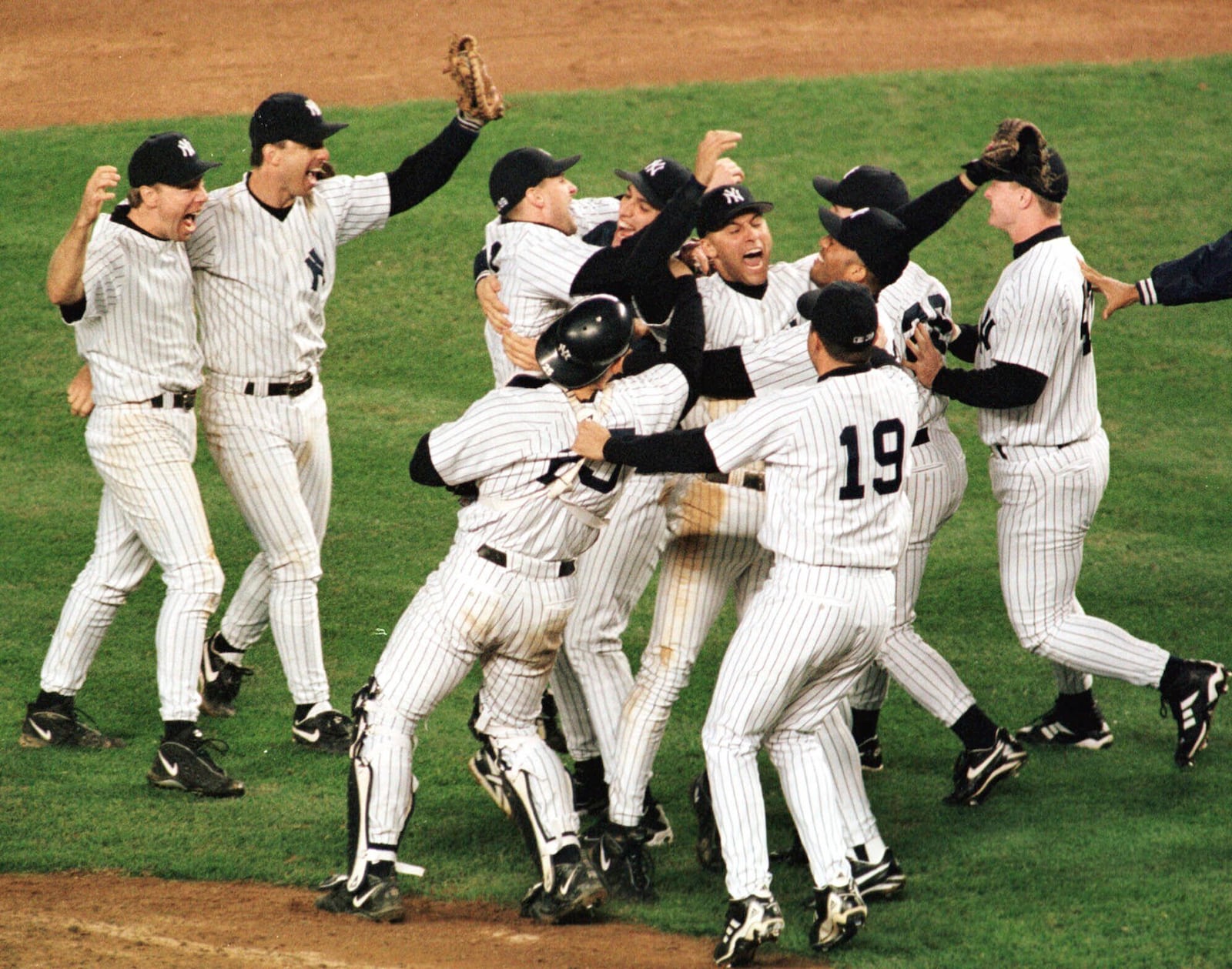 FILE - New York Yankees Derek Jeter is surrounded by teammates as they celebrate after defeating the Cleveland Indians 9-5 in Game 6 of the American League Championship Series Tuesday, Oct. 13, 1998 at Yankee Stadium in New York. (AP Photo/John Dunn, File)