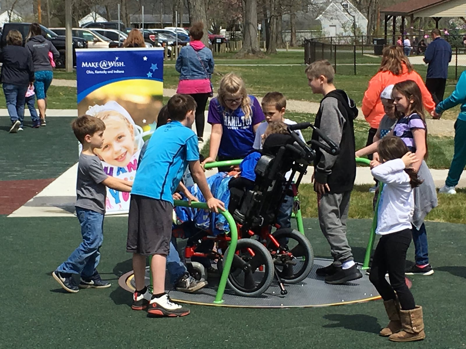 Grayson Combs, 10, gets ready to take a spin with some family and friends on an inclusive spinner that is accessible for children of all abilities. Grayson and his family joined Make-A-Wish Foundation to dedicate a piece of new wheelchair accessible playground equipment April 21 at Millikin Woods Park in Hamilton. He opted to use his wish to provide something all children could enjoy. ED RICHTER/STAFF