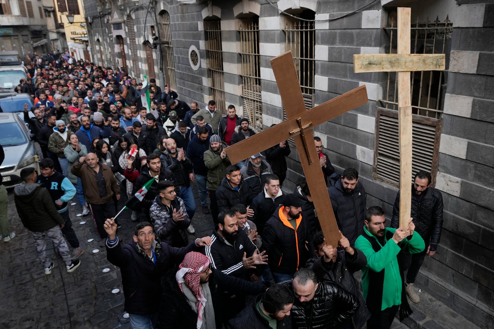 Syrian Christians carry crosses and shout slogans in Damascus, Syria, Tuesday, Dec. 24, 2024, as they march during a protest after a Christmas tree was set on fire in Hamah city on Sunday. (AP Photo/Hussein Malla)