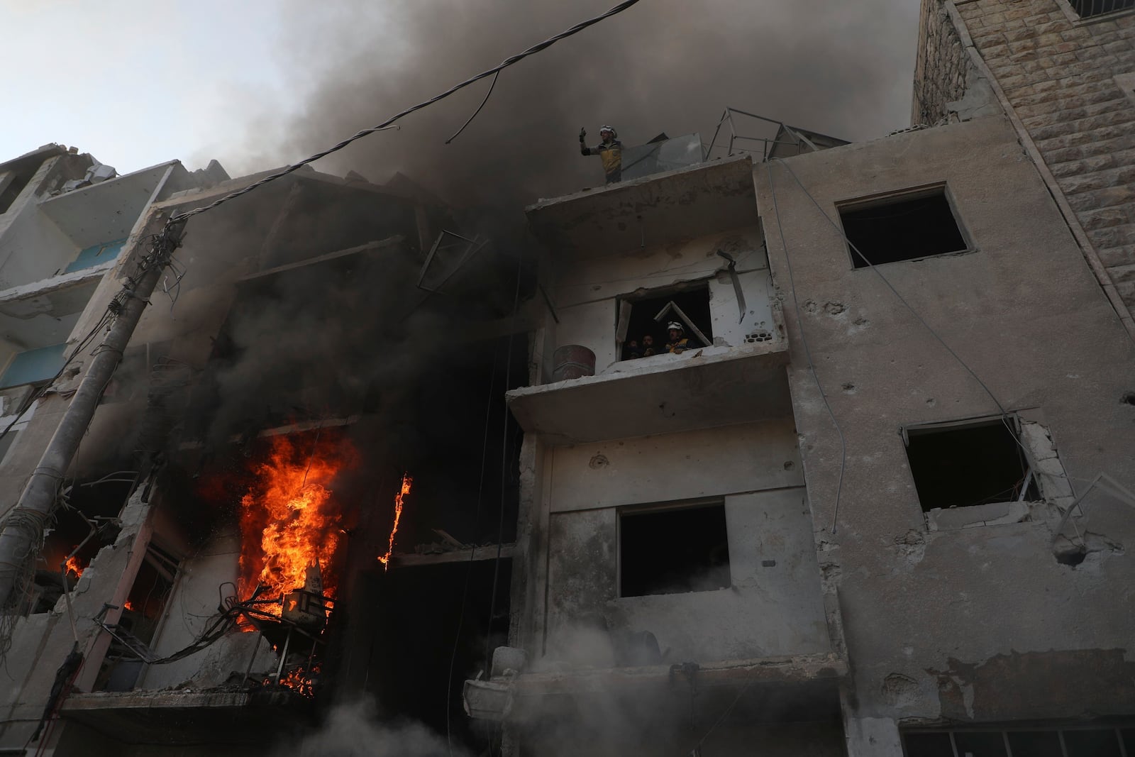 This photo provided by the Syrian Civil Defence White Helmets, which has been authenticated based on its contents and other AP reporting, shows Syrian White Helmet civil defence workers stand in a burning building after the Syrian government forces hit Idlib city, Syria, Monday, Dec. 2, 2024. (Syrian Civil Defence White Helmets via AP)