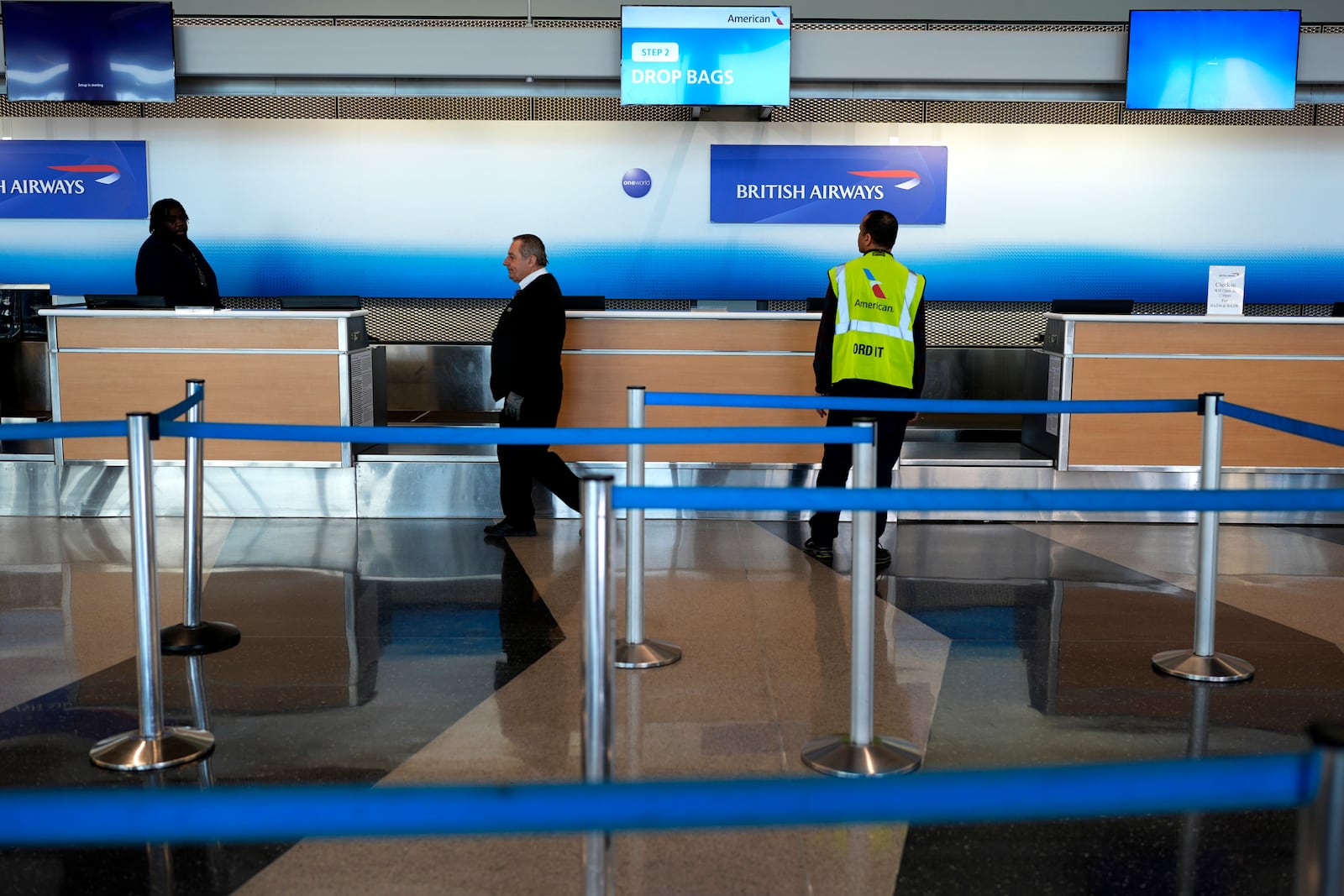 Airport employees work as information sign is displayed at British Airways ticket counter at O'Hare International Airport in Chicago, Friday, March 21, 2025. (AP Photo/Nam Y. Huh)