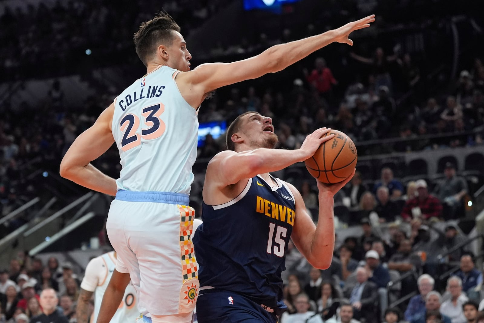 Denver Nuggets center Nikola Jokic (15) drives to the basket against San Antonio Spurs forward Zach Collins (23) during the first half of an NBA basketball game in San Antonio, Saturday, Jan. 4, 2025. (AP Photo/Eric Gay)