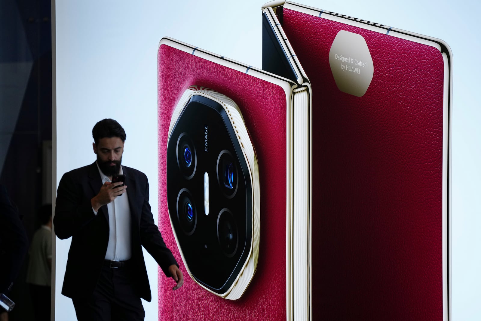 Visitors walk in front of a giant billboard display of Huawei's industry's first tri-foldable phone during the opening of its global sales in Kuala Lumpur, Malaysia, Tuesday, Feb. 18, 2025. (AP Photo/Vincent Thian)