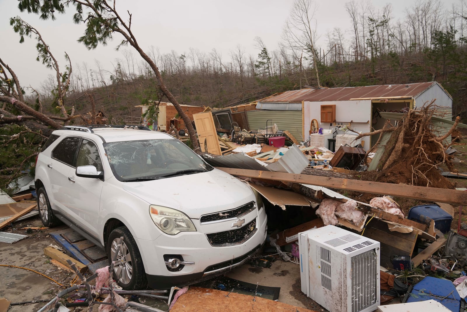 A vehicle sits in front of a damaged home and debris from a severe storm is seen Saturday, March 15, 2025, in Wayne County, Mo. (AP Photo/Jeff Roberson)